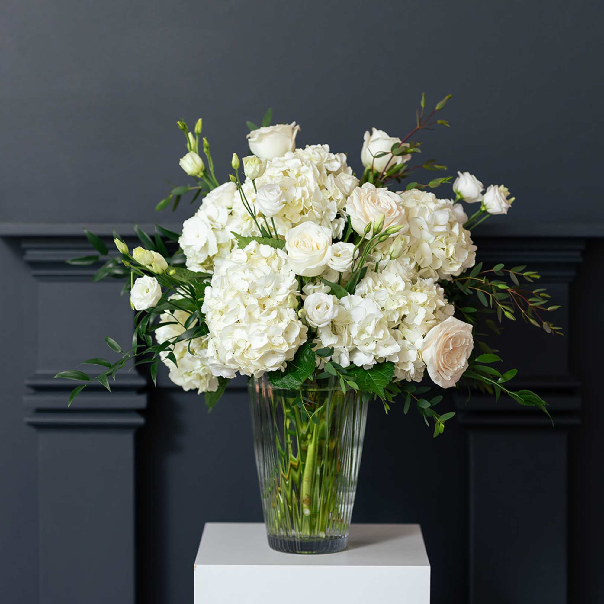 White roses and hydrangeas arranged in a clear glass vase