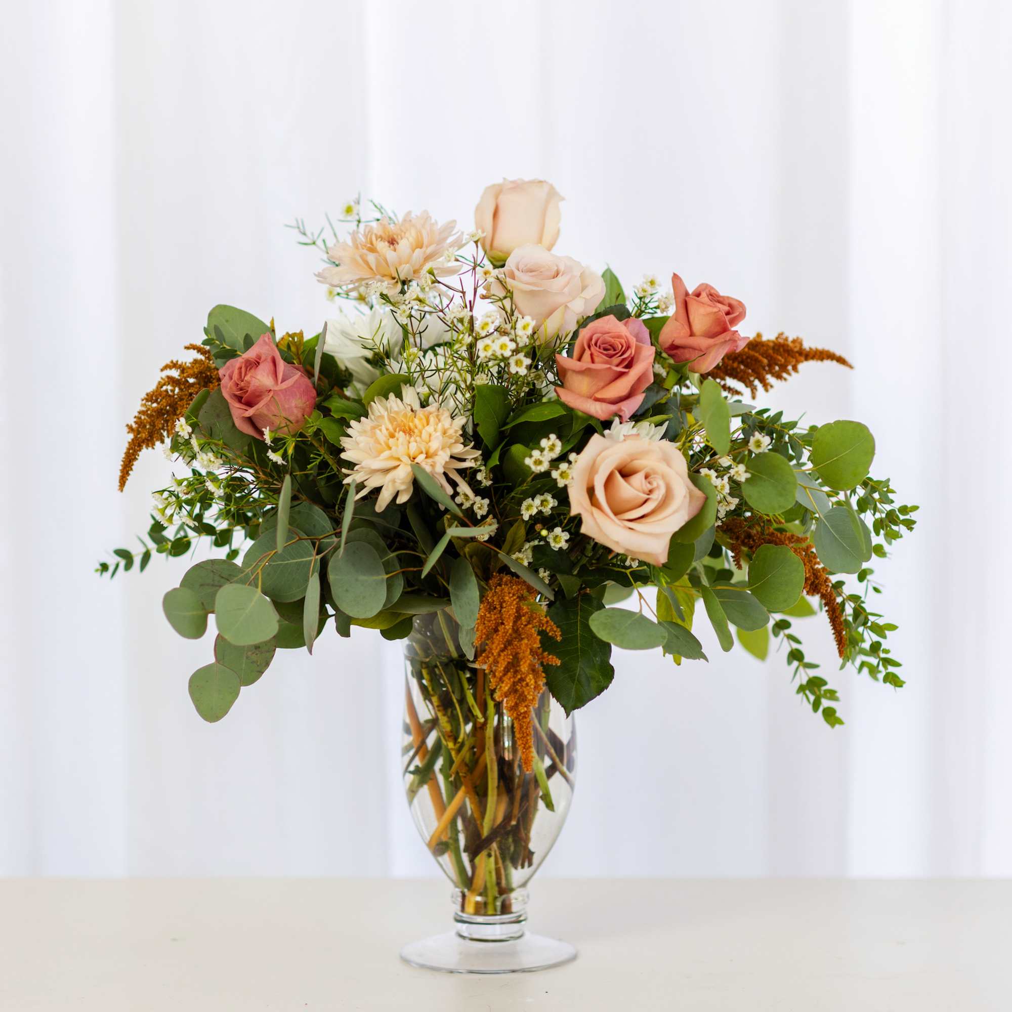 Mixed bouquet of peach and pink roses in a clear glass vase