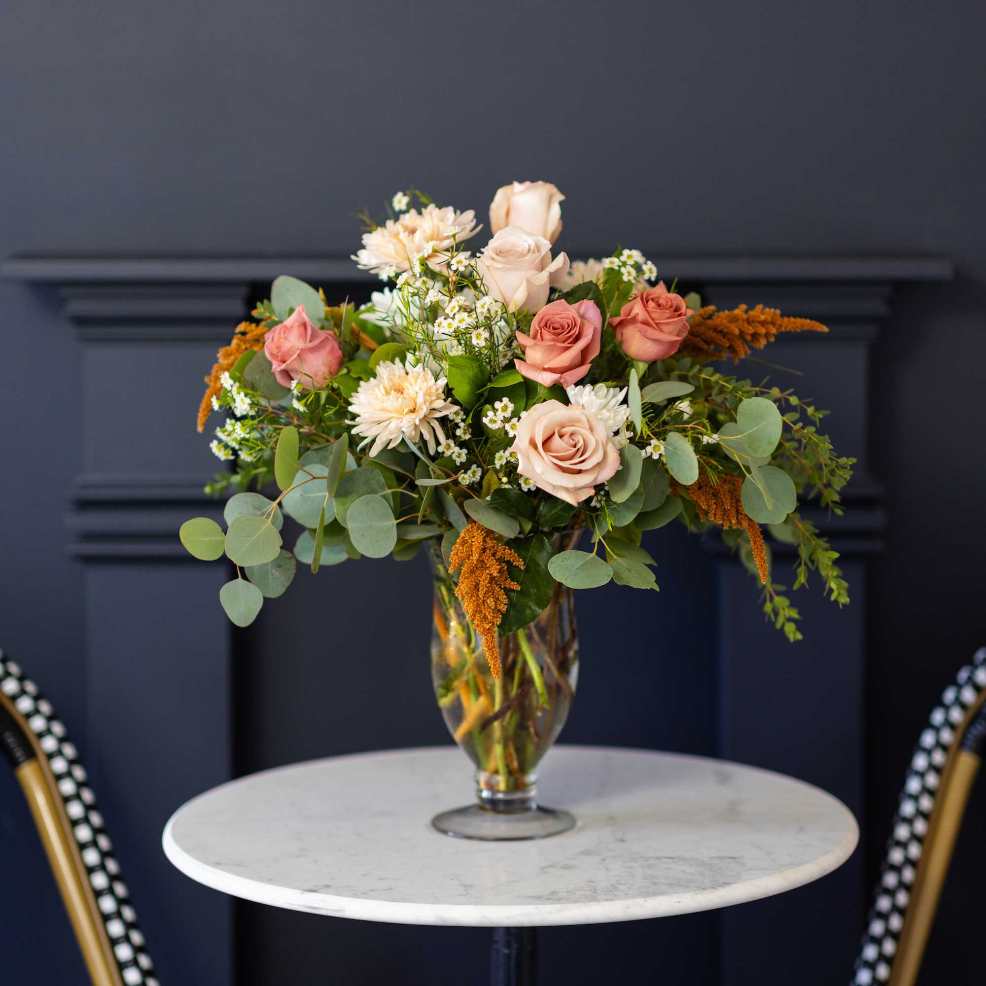 Mixed bouquet of blush roses and white flowers in a glass vase