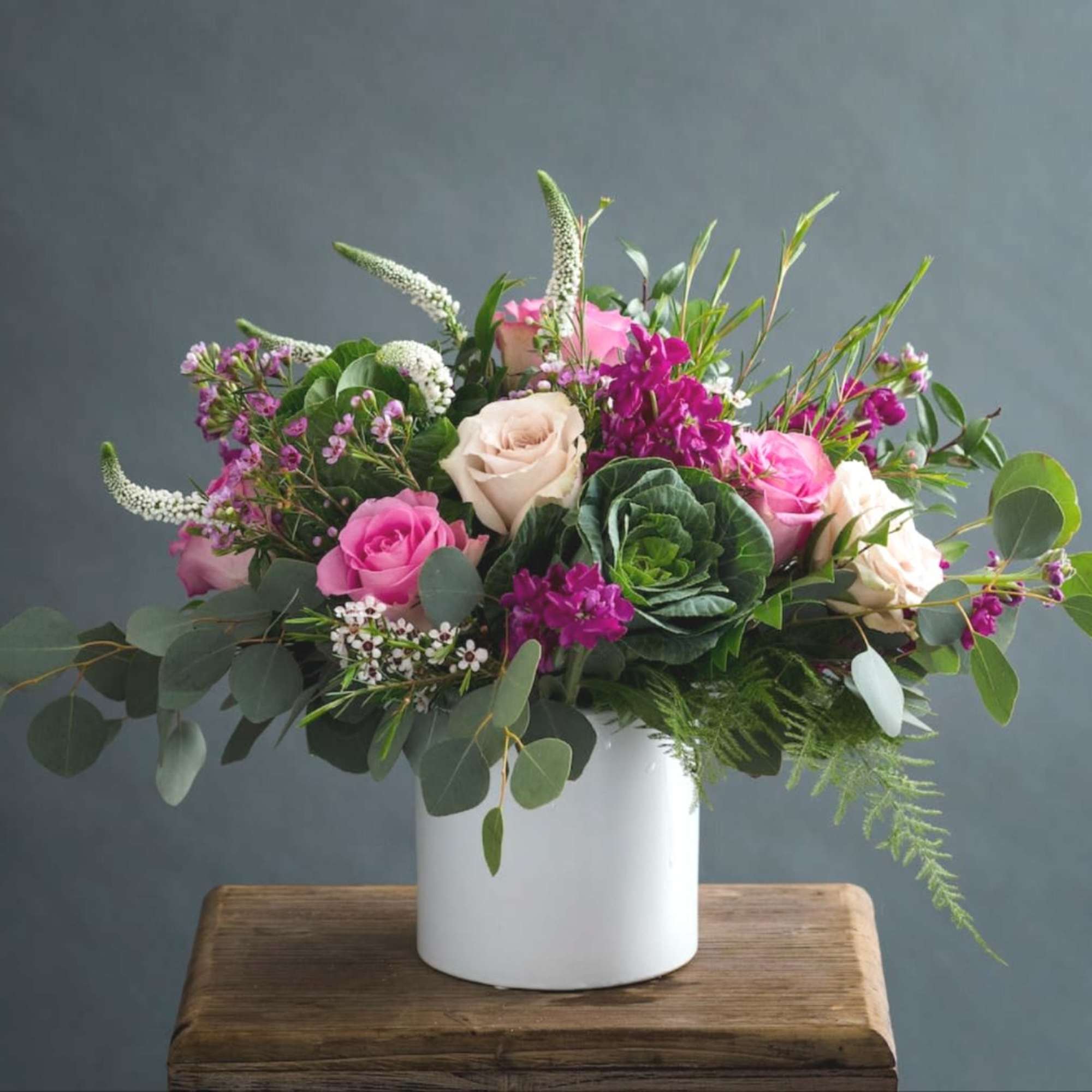 Pink and cream roses in a white vase with mixed greenery
