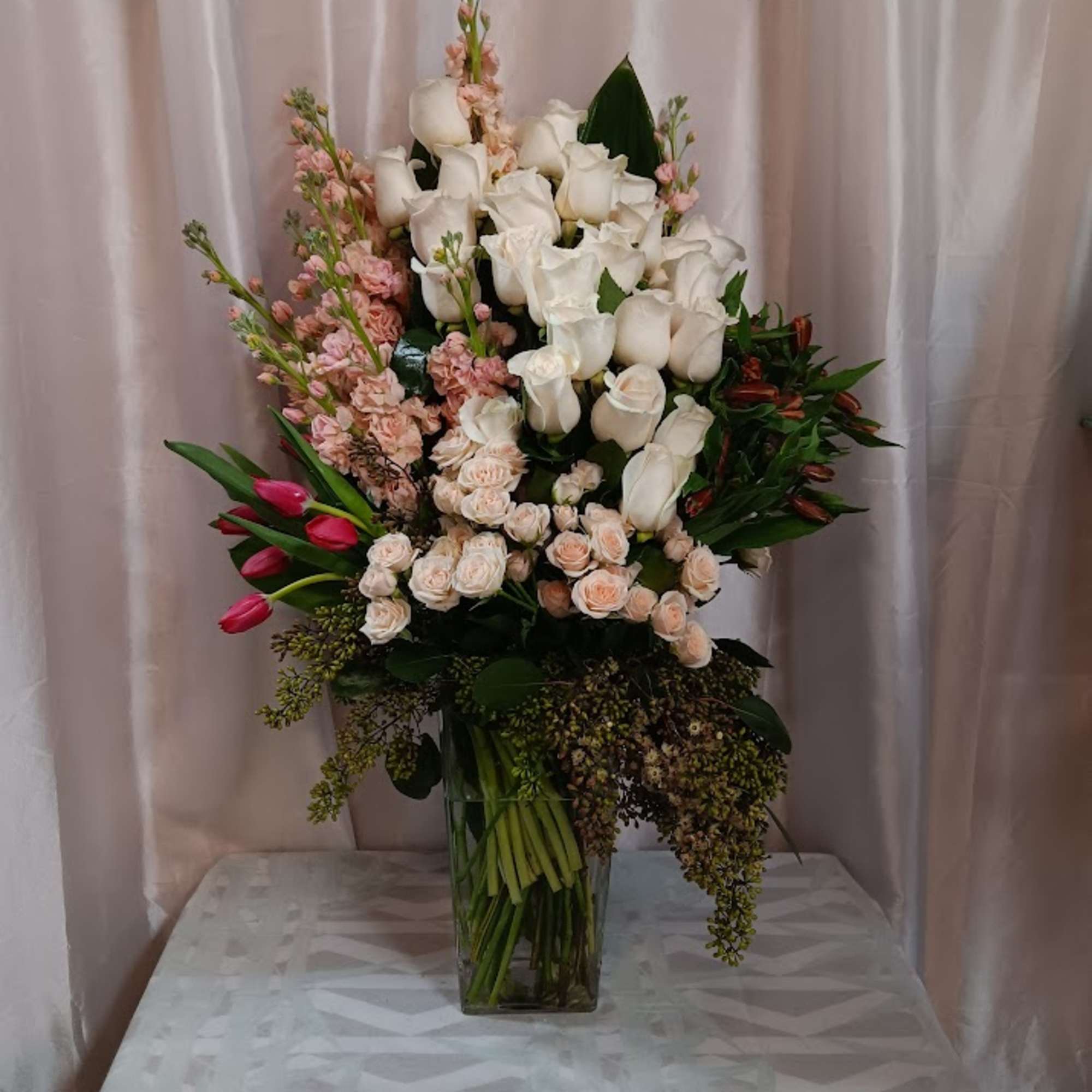 This arrangement contains alstroemeria, tulips, roses, and other seasonal blooms. APPROXIMATE DIMENSIONS: