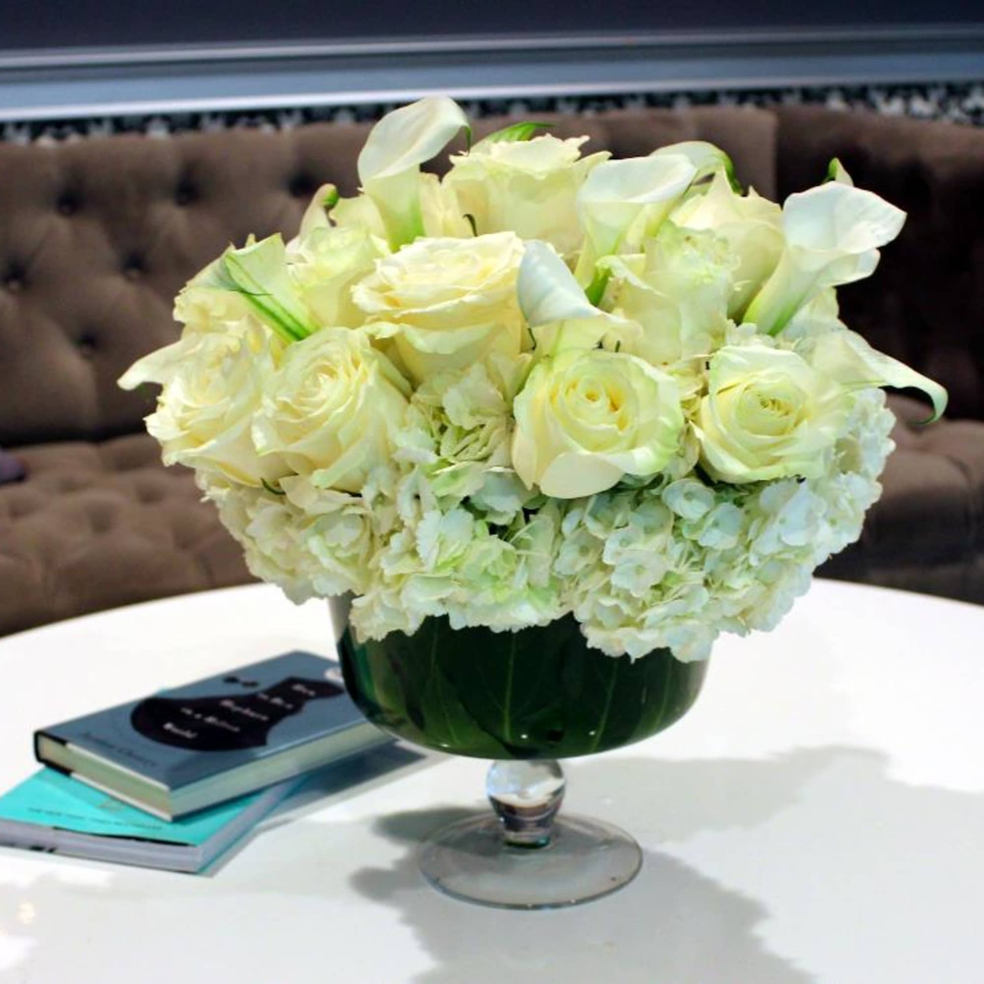 White roses and calla lilies arranged in a glass vase