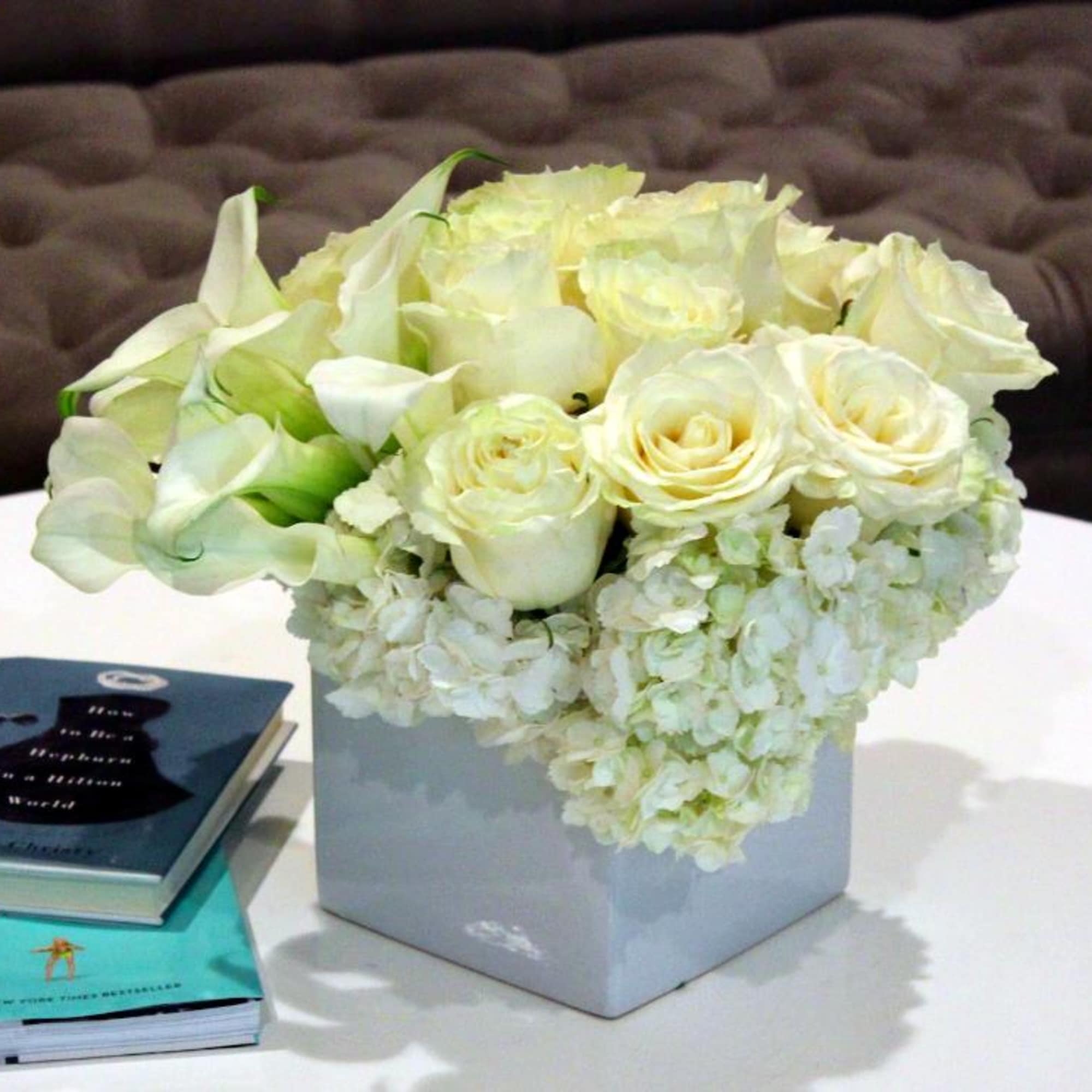 White roses and calla lilies in a square vase