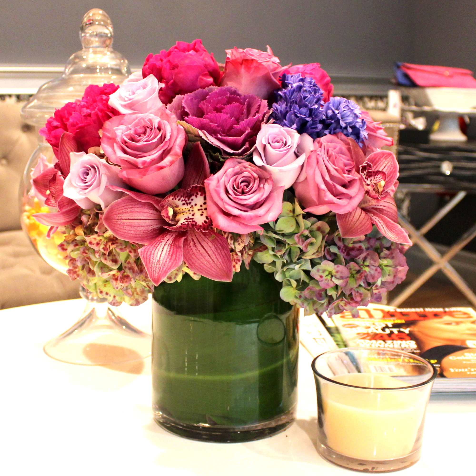 Pink and purple flower arrangement in a green glass vase