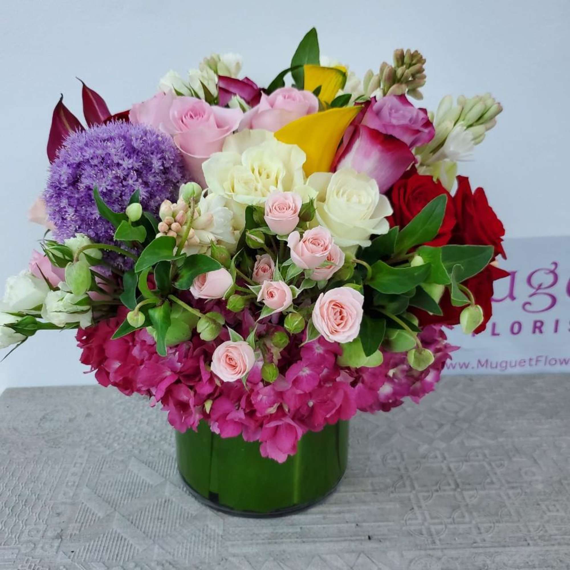 Mixed bouquet of pink, white, purple, and red flowers in a green vase