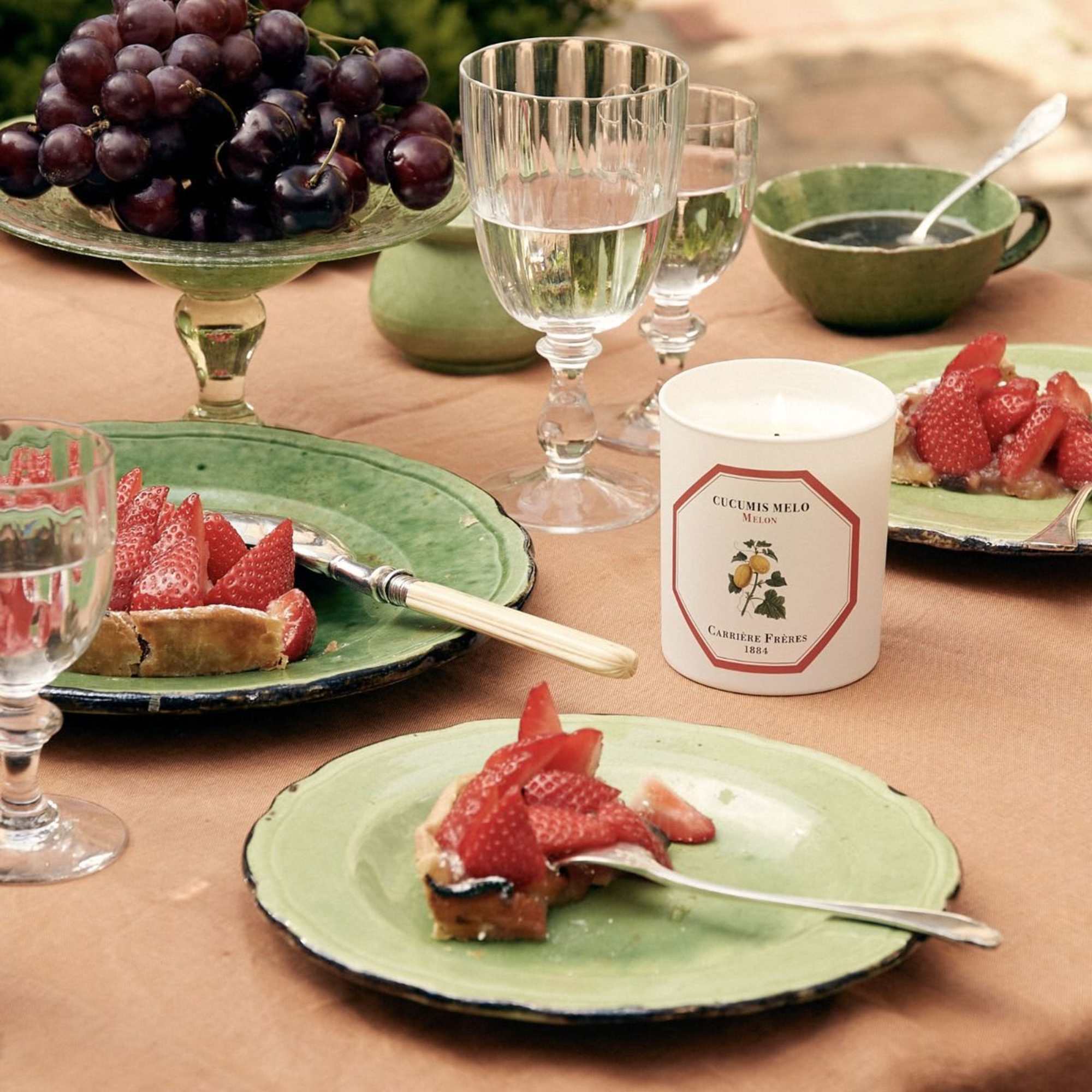 Table setting with strawberries, grapes, glasses, and a candle