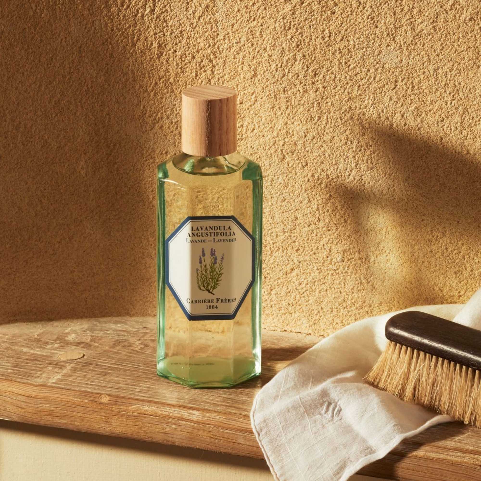 Lavender perfume bottle with a wooden cap beside a brush and cloth