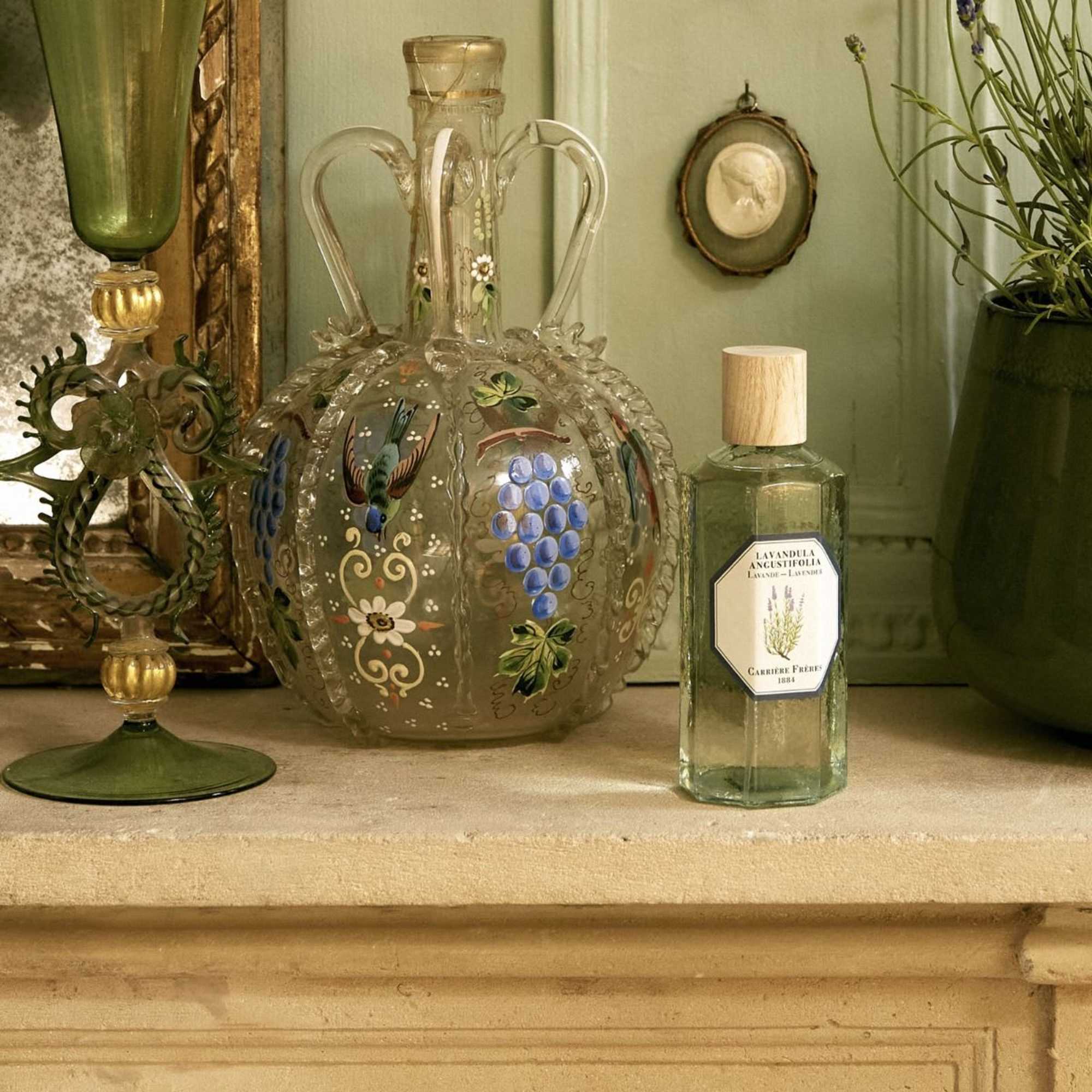 Decorative glass bottles and a painted glass vase on a shelf