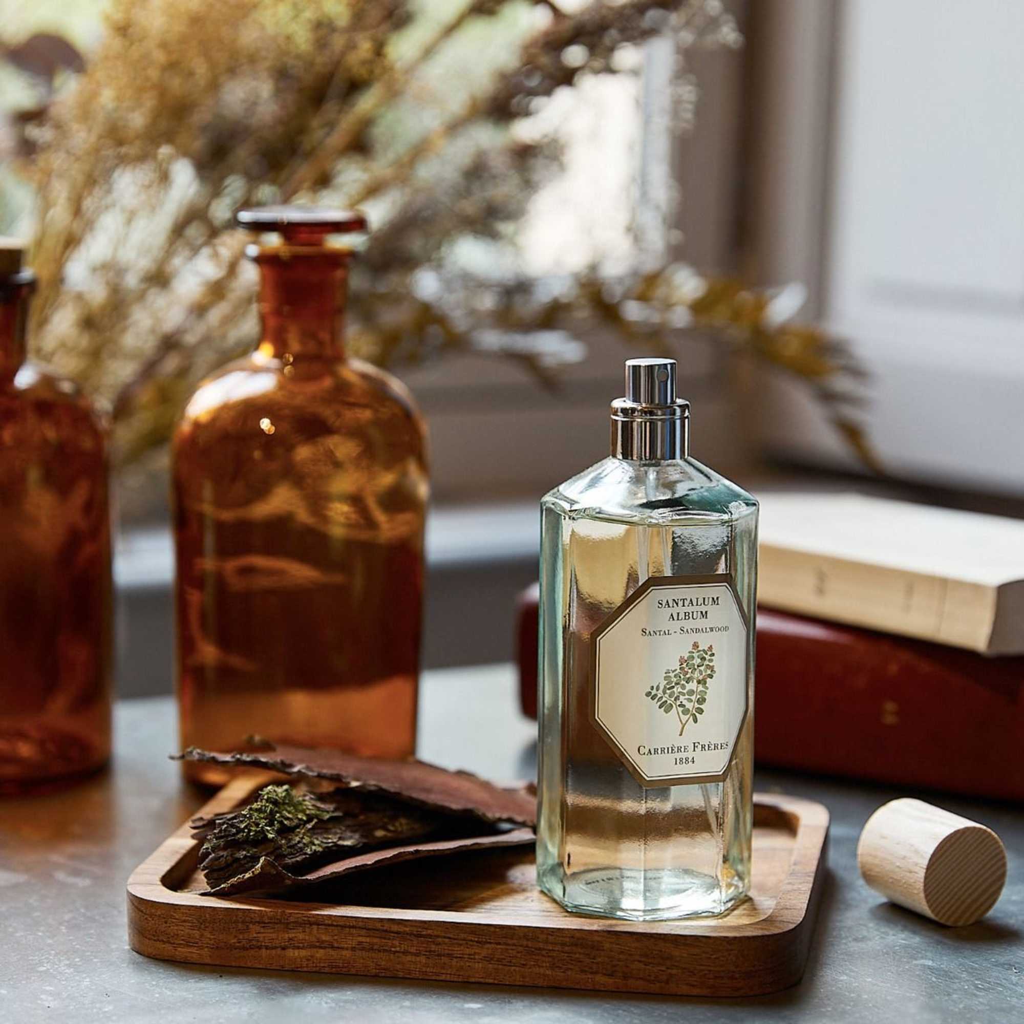 Glass perfume bottle on a wooden tray with amber bottles in the background