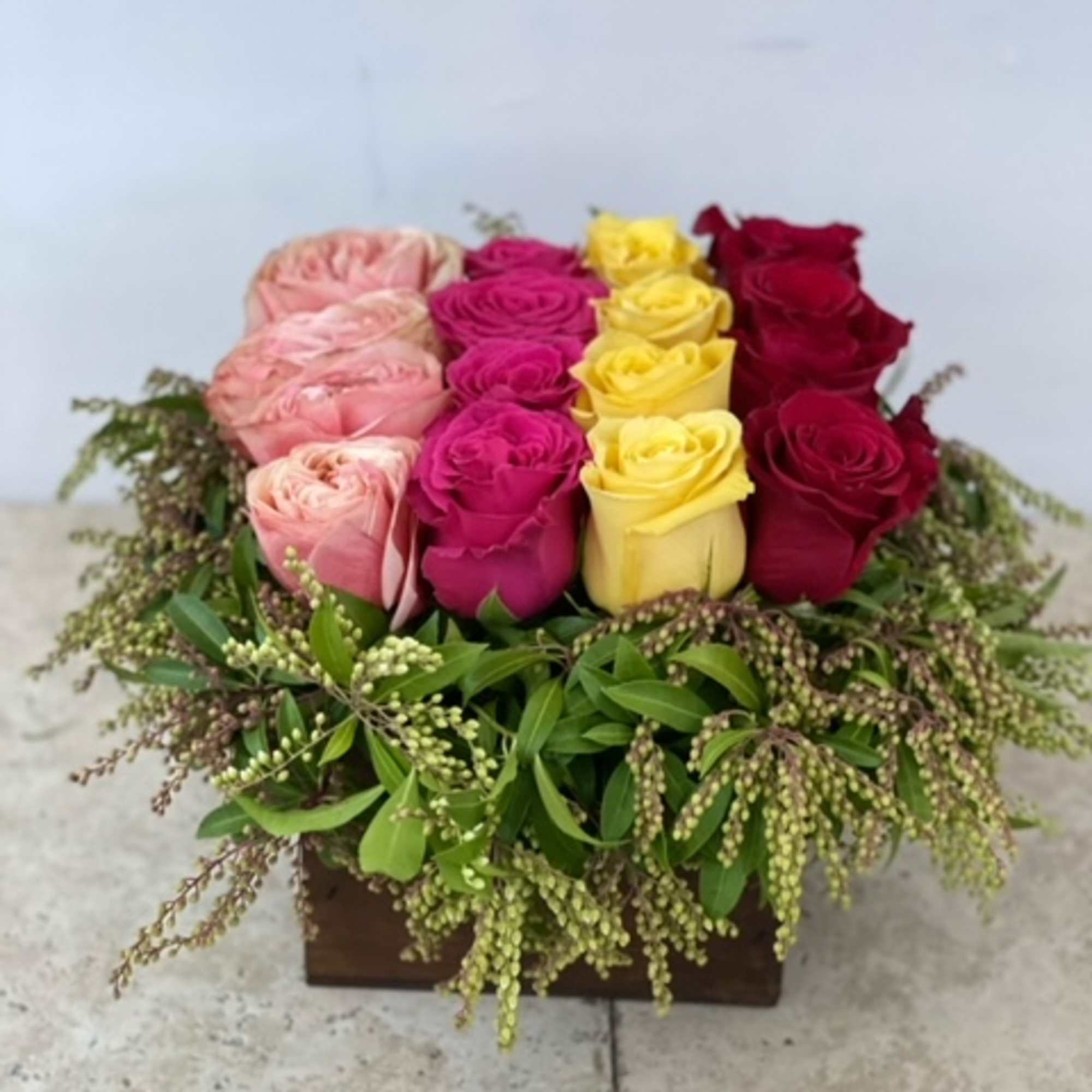 Box arrangement of pink, magenta, yellow, and red roses