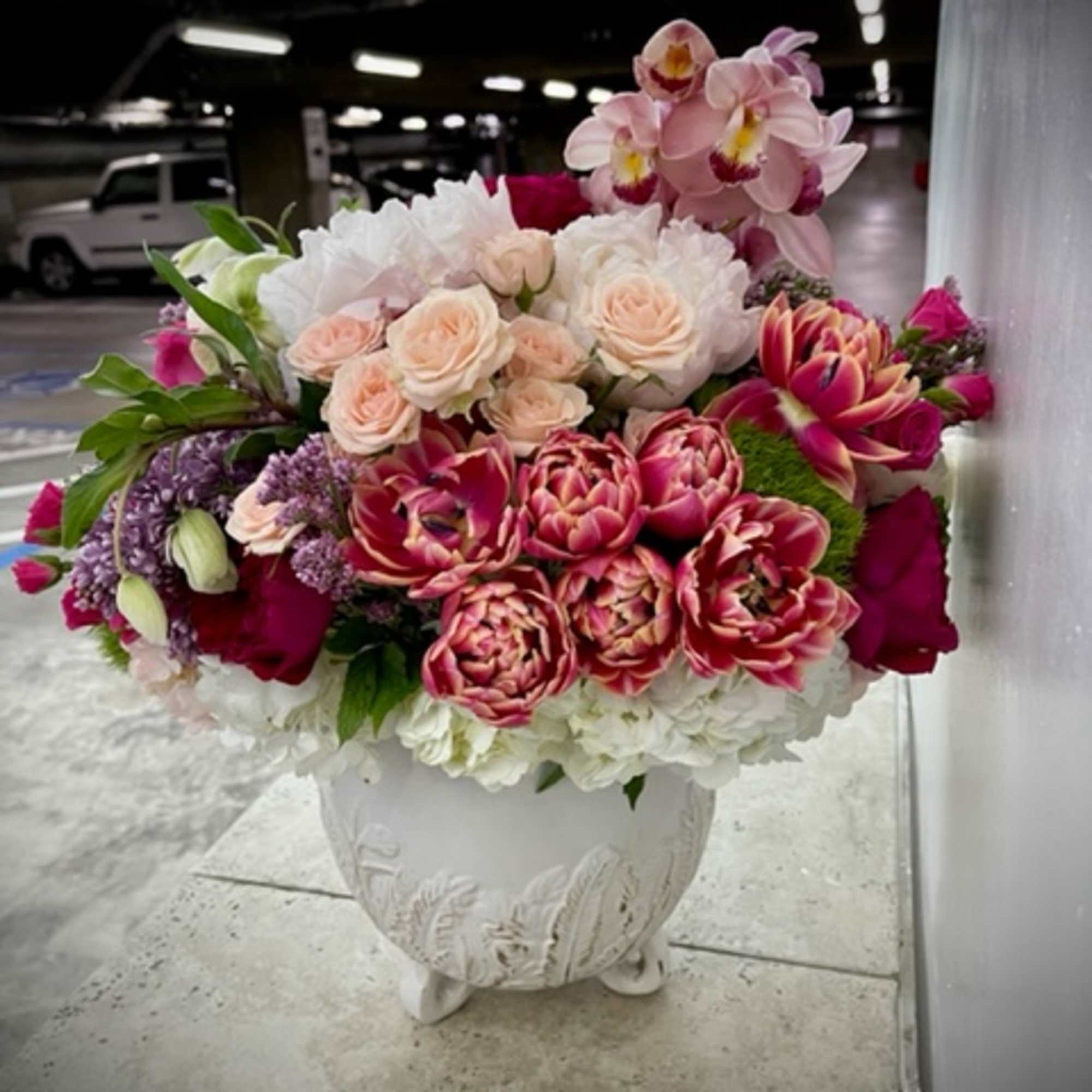 Large pink and white floral arrangement in a white urn