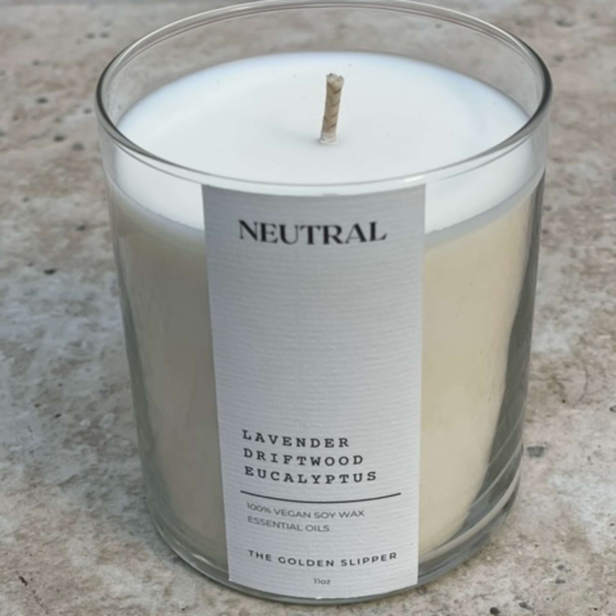 A white candle in a clear glass jar with a label reading Neutral.