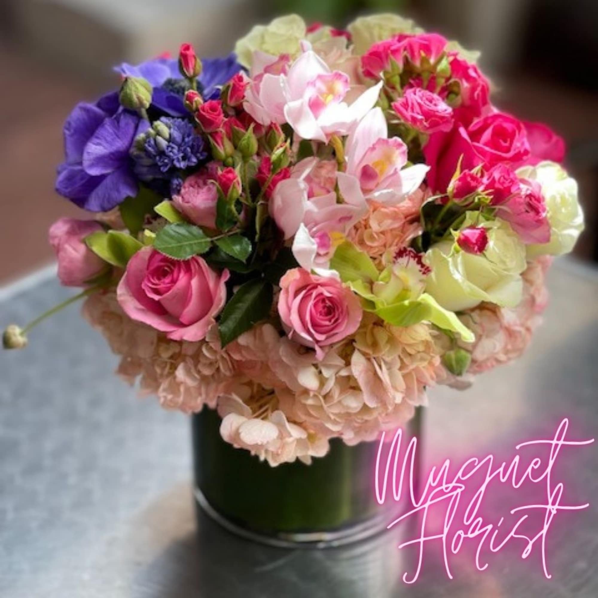 Mixed bouquet of pink, purple, and white flowers in a dark vase