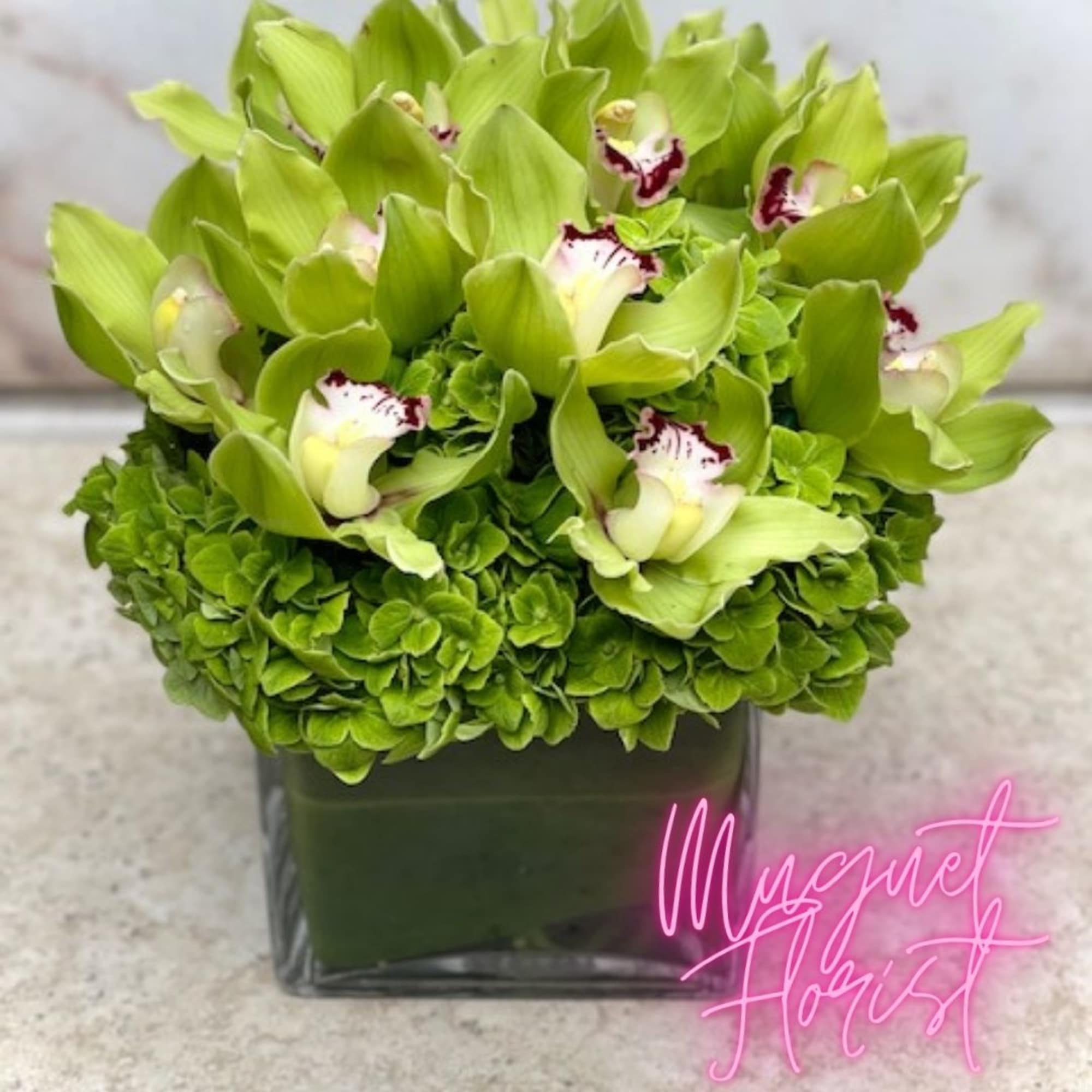 Green orchid blooms arranged in a square glass vase, photo 3 of 5