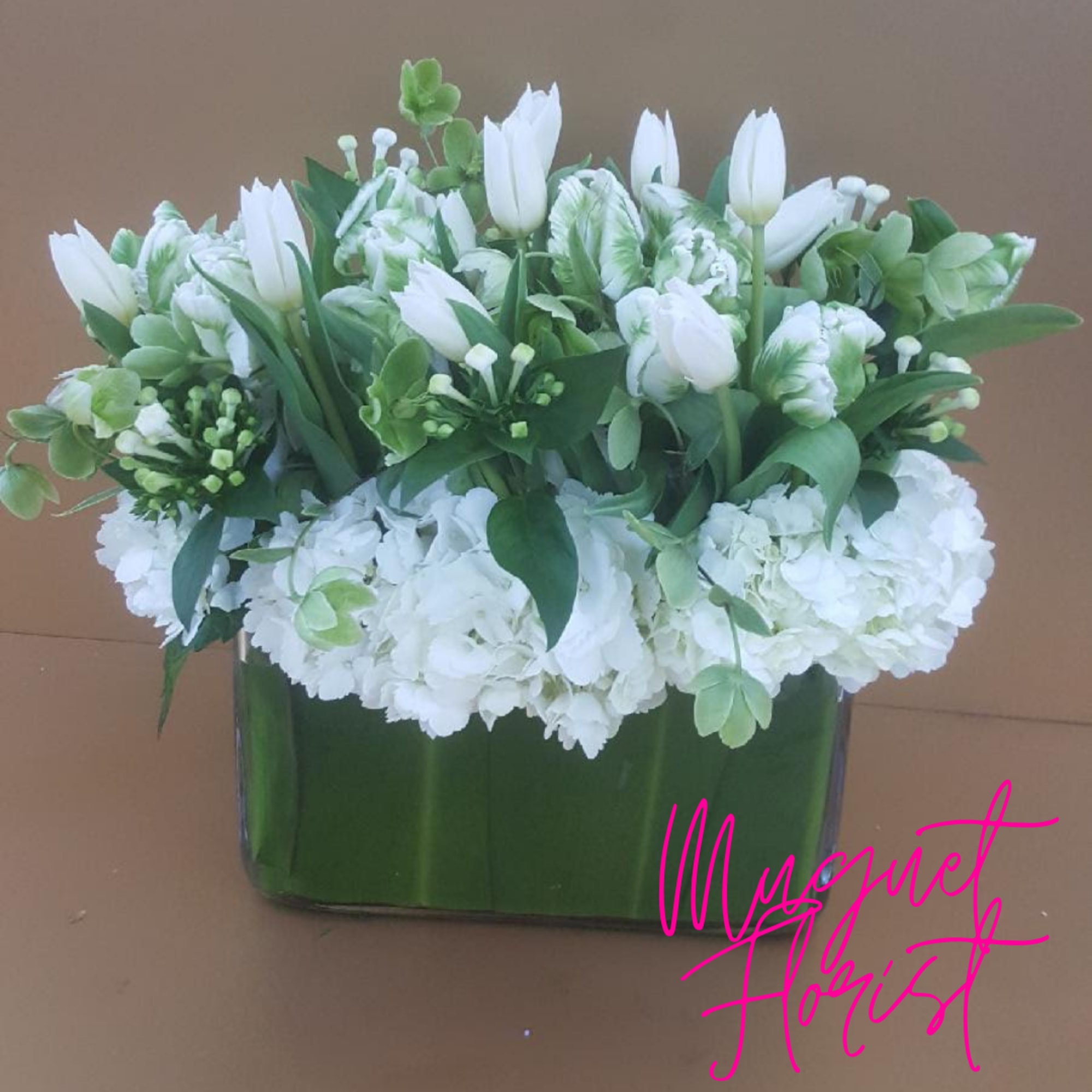 White tulips and hydrangeas arranged in a rectangular glass vase