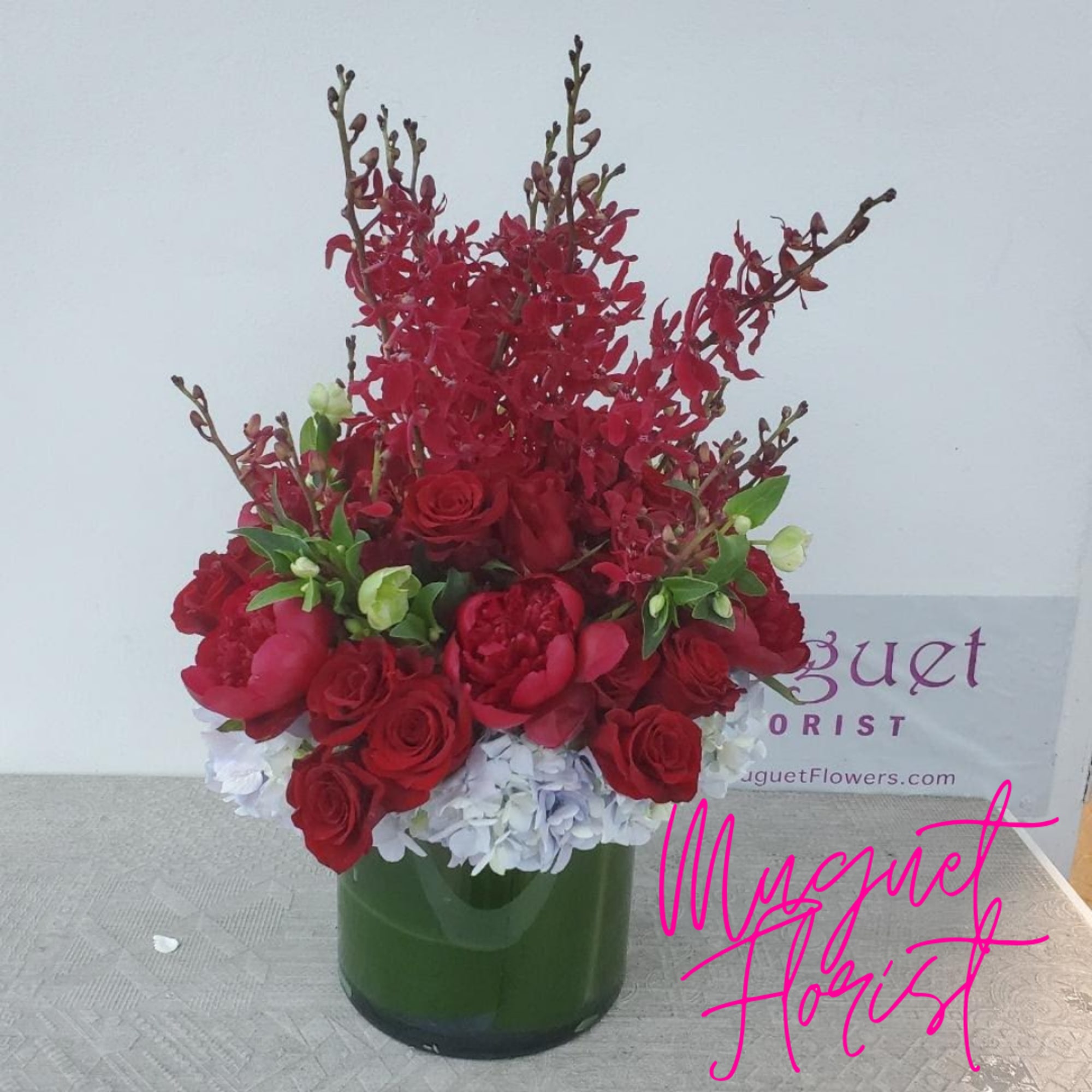 Red floral arrangement in a green vase with white flowers at the base