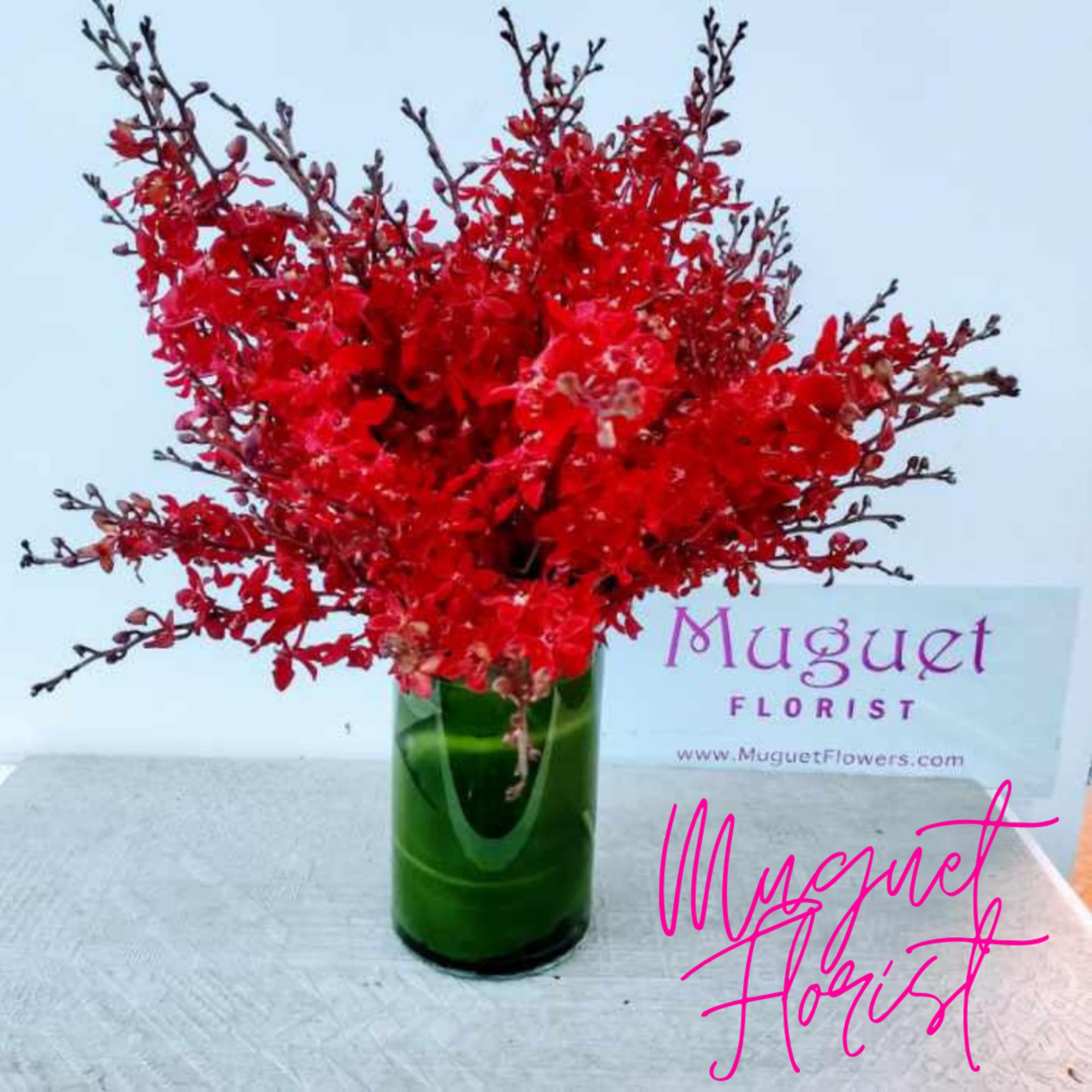 Red floral arrangement in a green glass vase