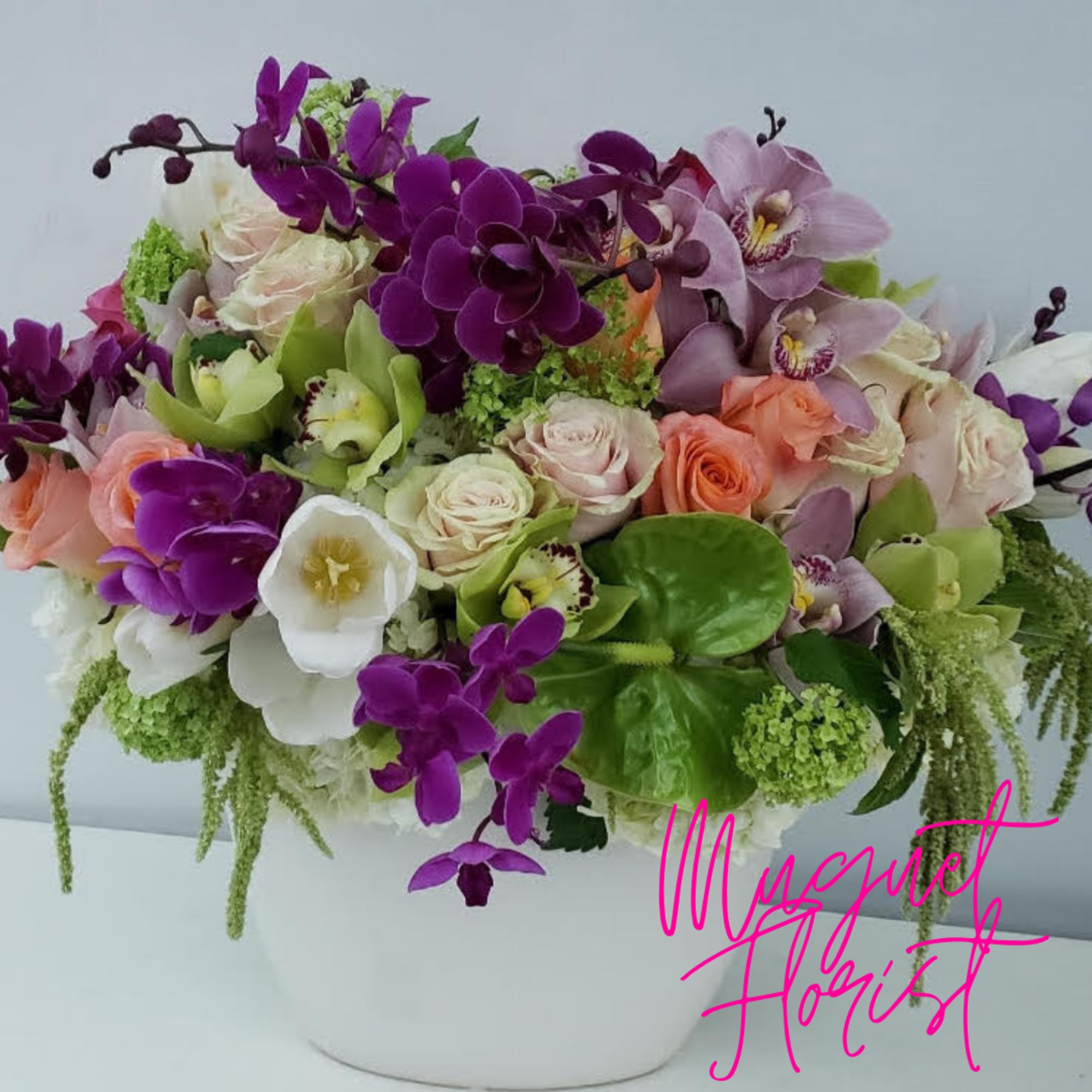 Mixed bouquet of orchids, roses, and calla lilies in a white vase