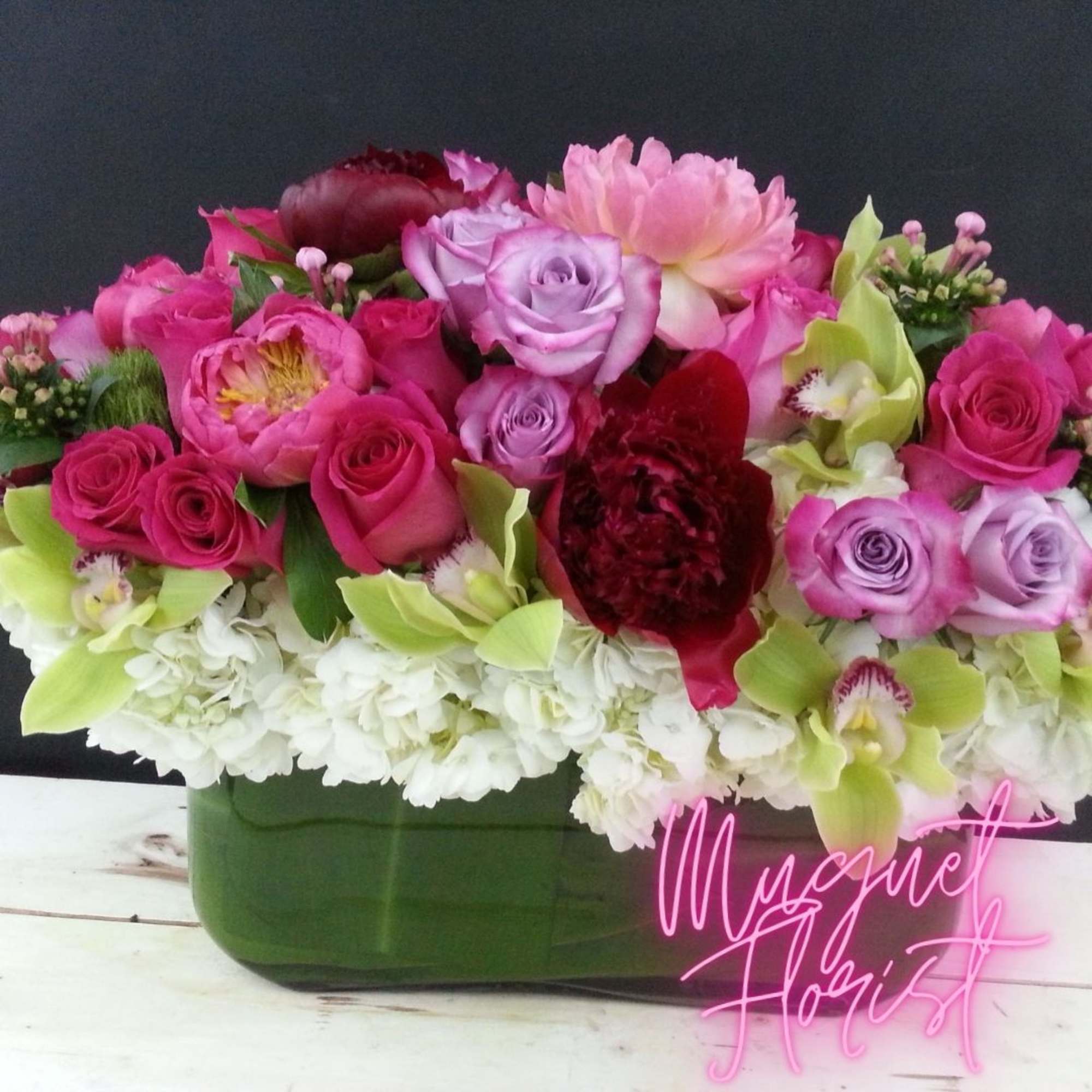 Pink and lavender roses with orchids in a green vase