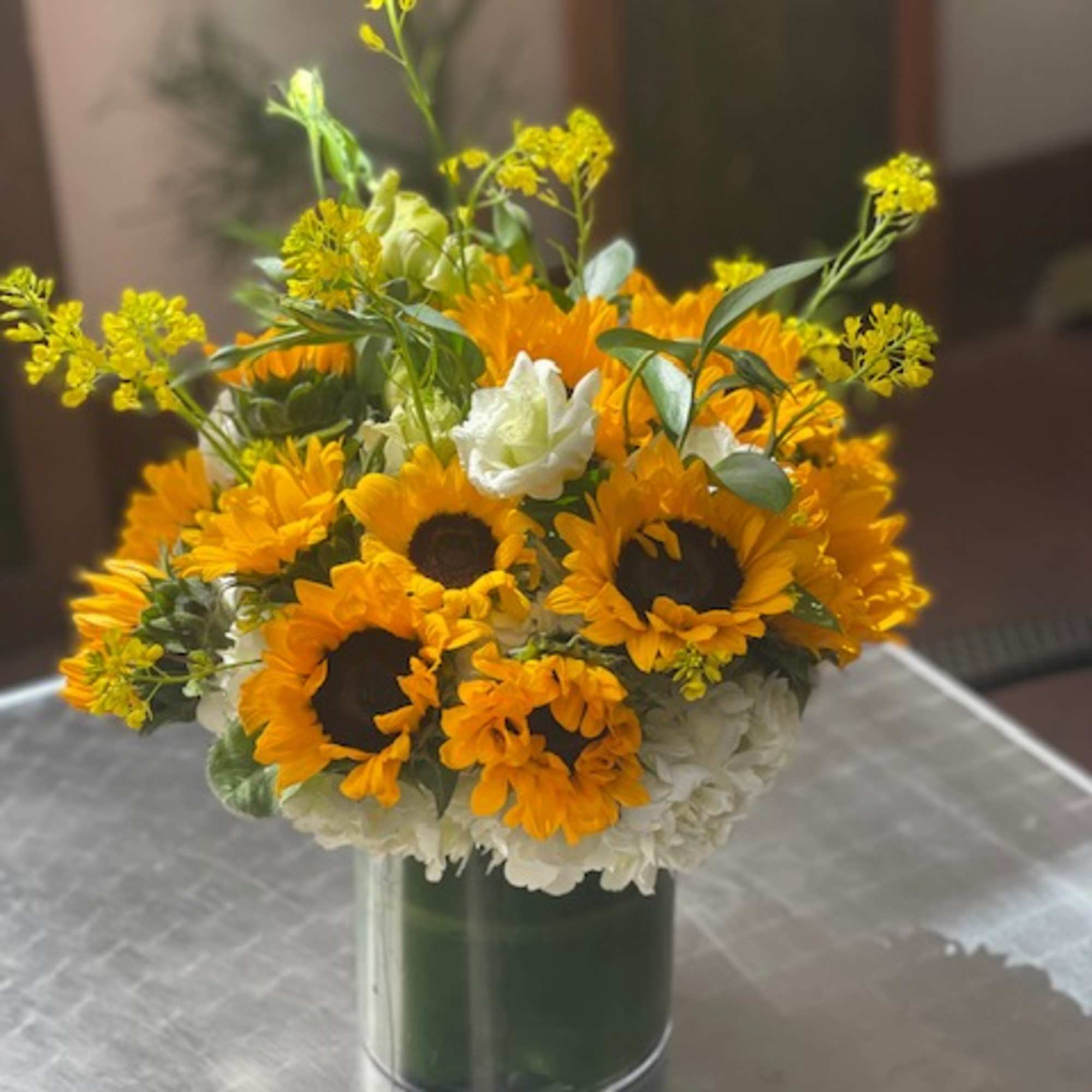 Sunflower bouquet in a glass vase with white blooms and yellow accents