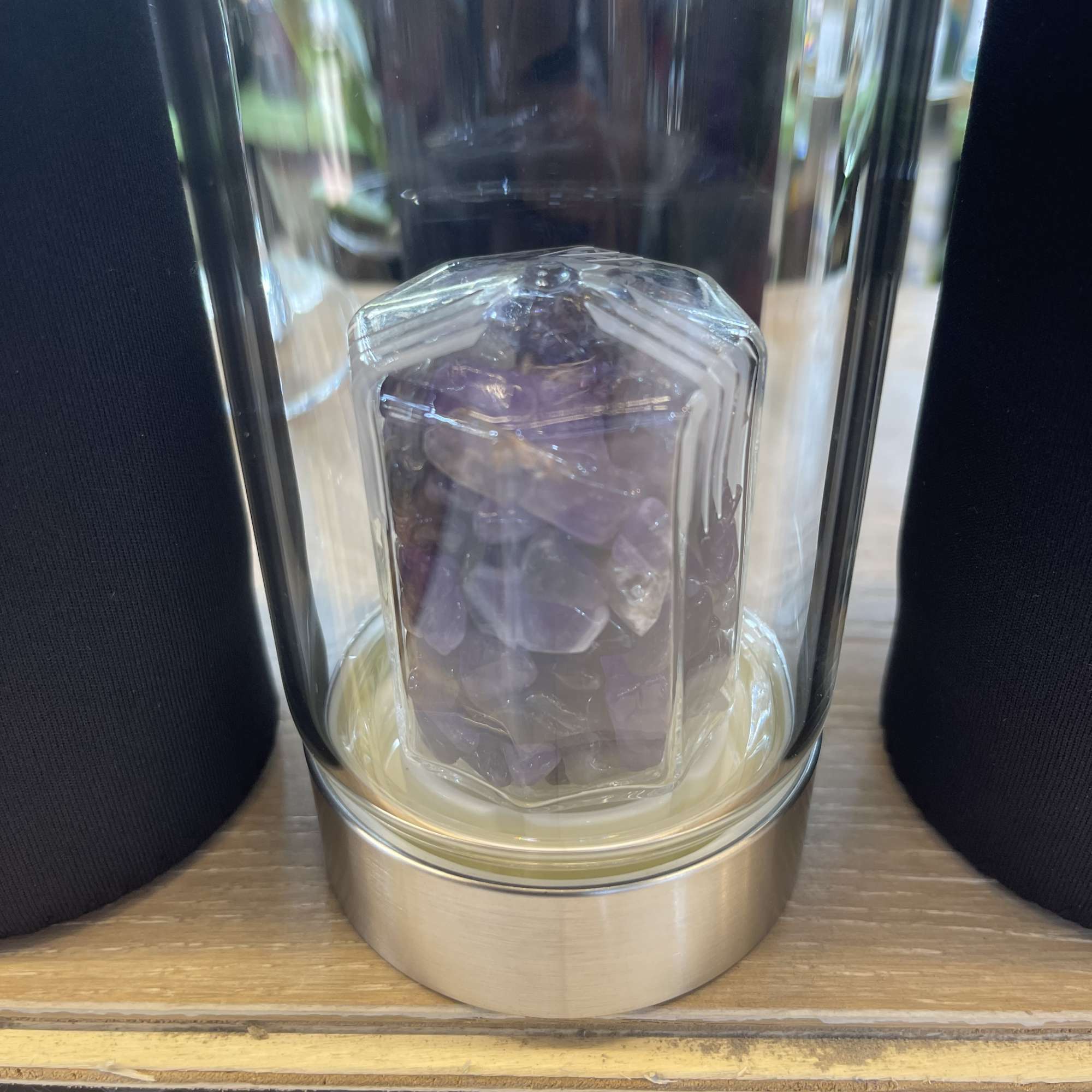 Purple crystal cluster inside a glass dome on a metal base