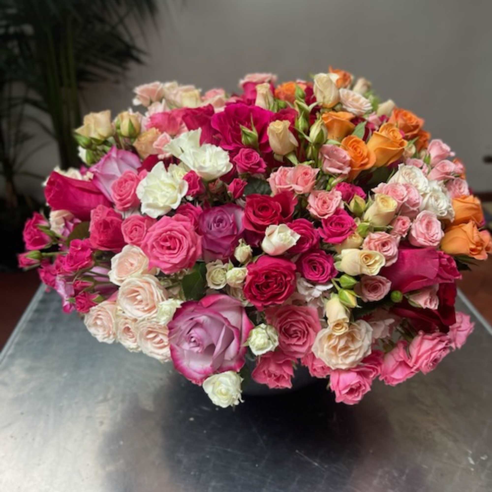 Large bouquet of pink, white, and orange roses in a low container