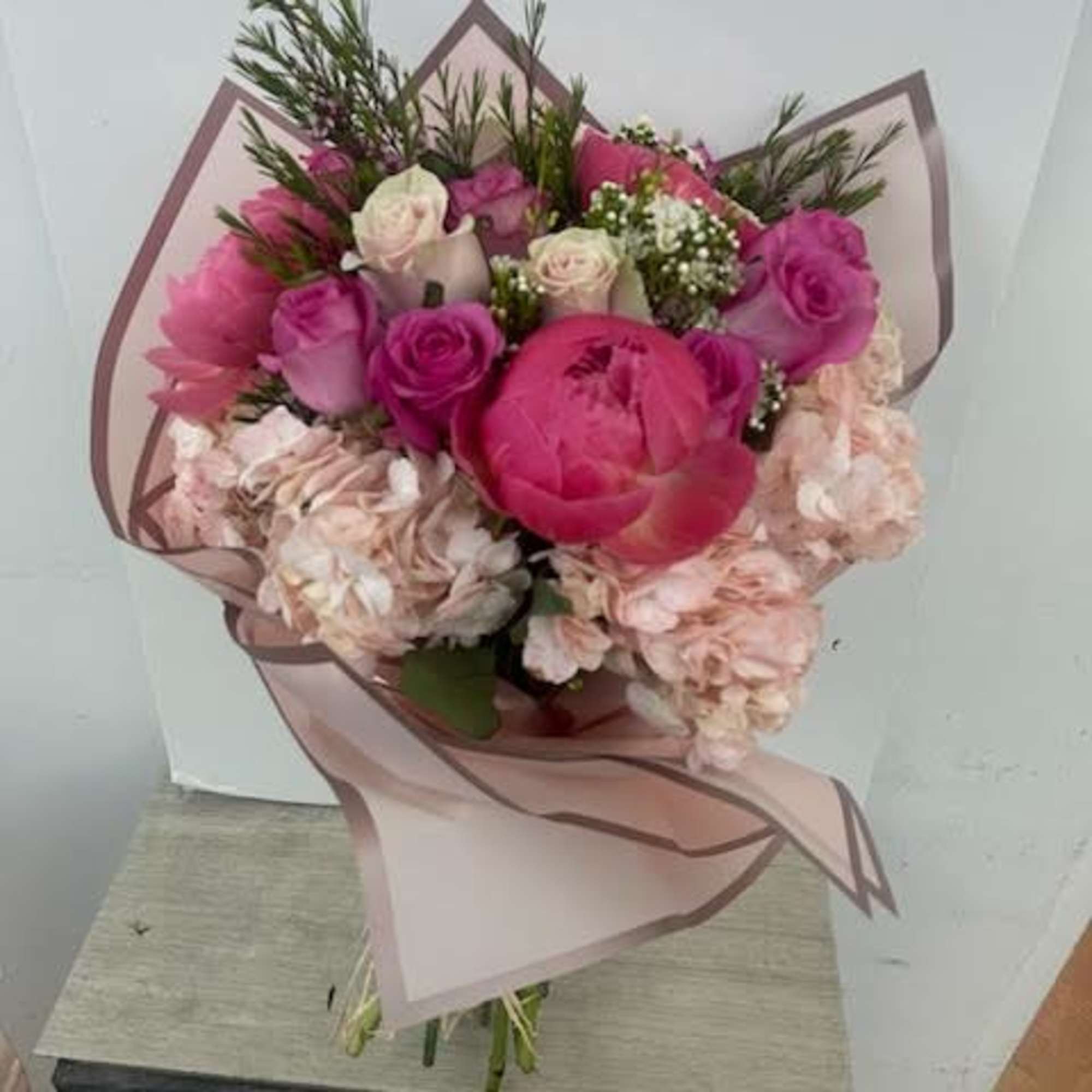 Pink and blush bouquet of roses and hydrangeas wrapped in sheer paper