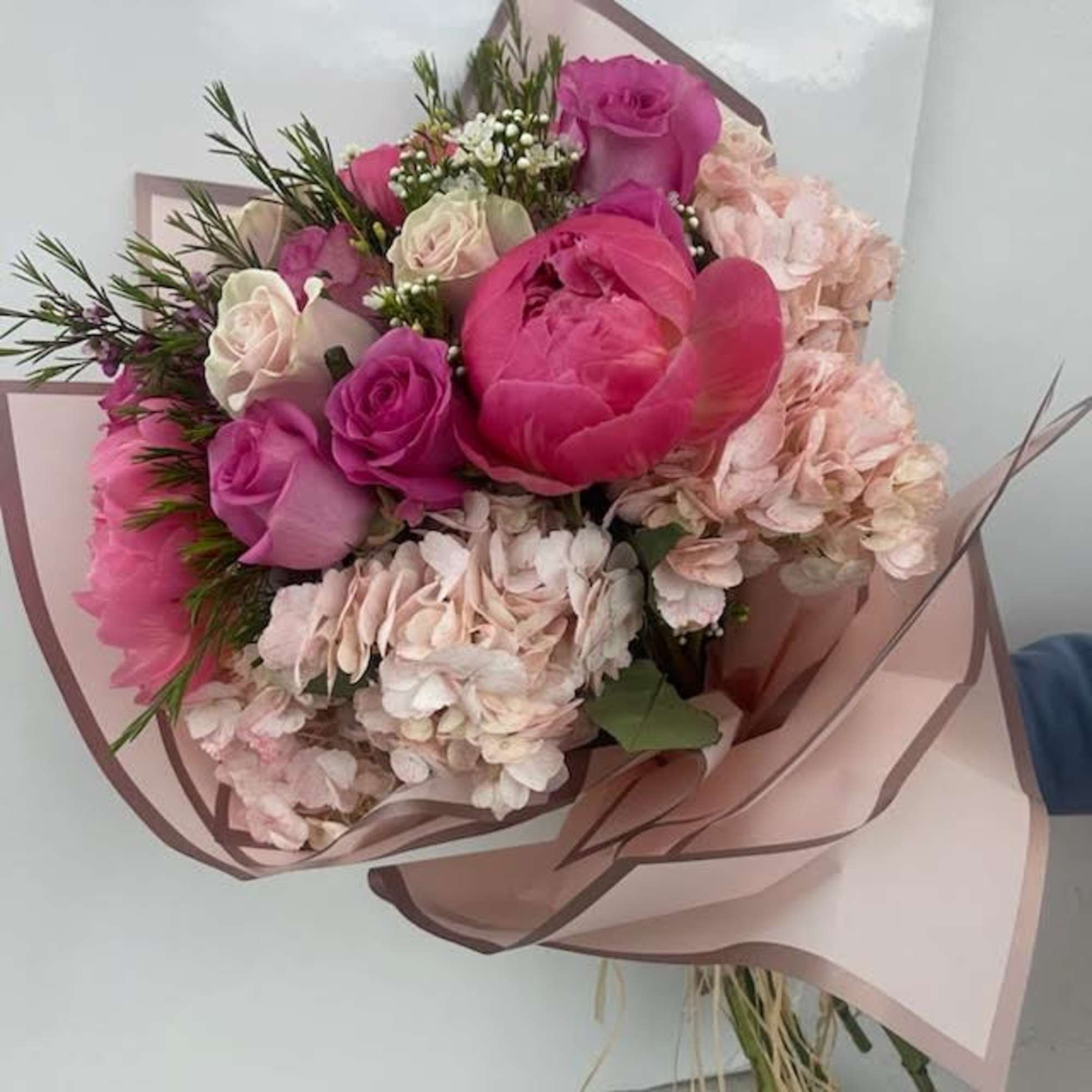 Bouquet of pink and white roses with pale hydrangeas in pink wrap