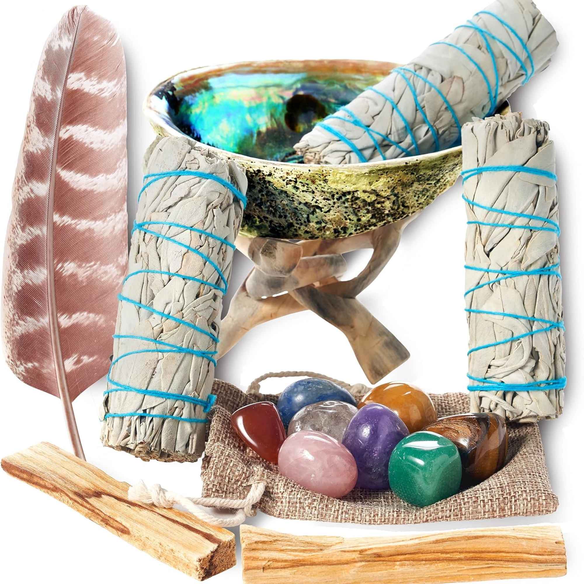 Smudge sticks, a feather, a shell bowl, and polished stones arranged on a white background
