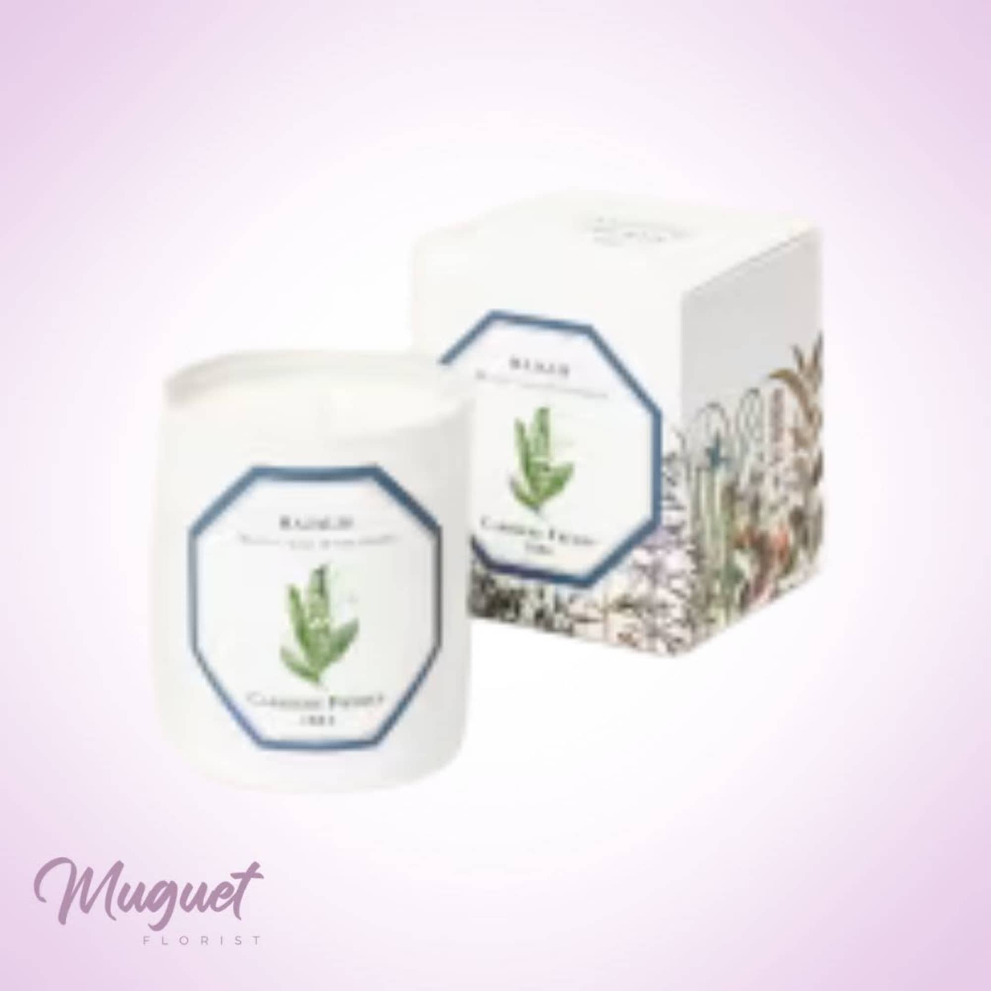 White candle jar and matching box with floral label on a pink background