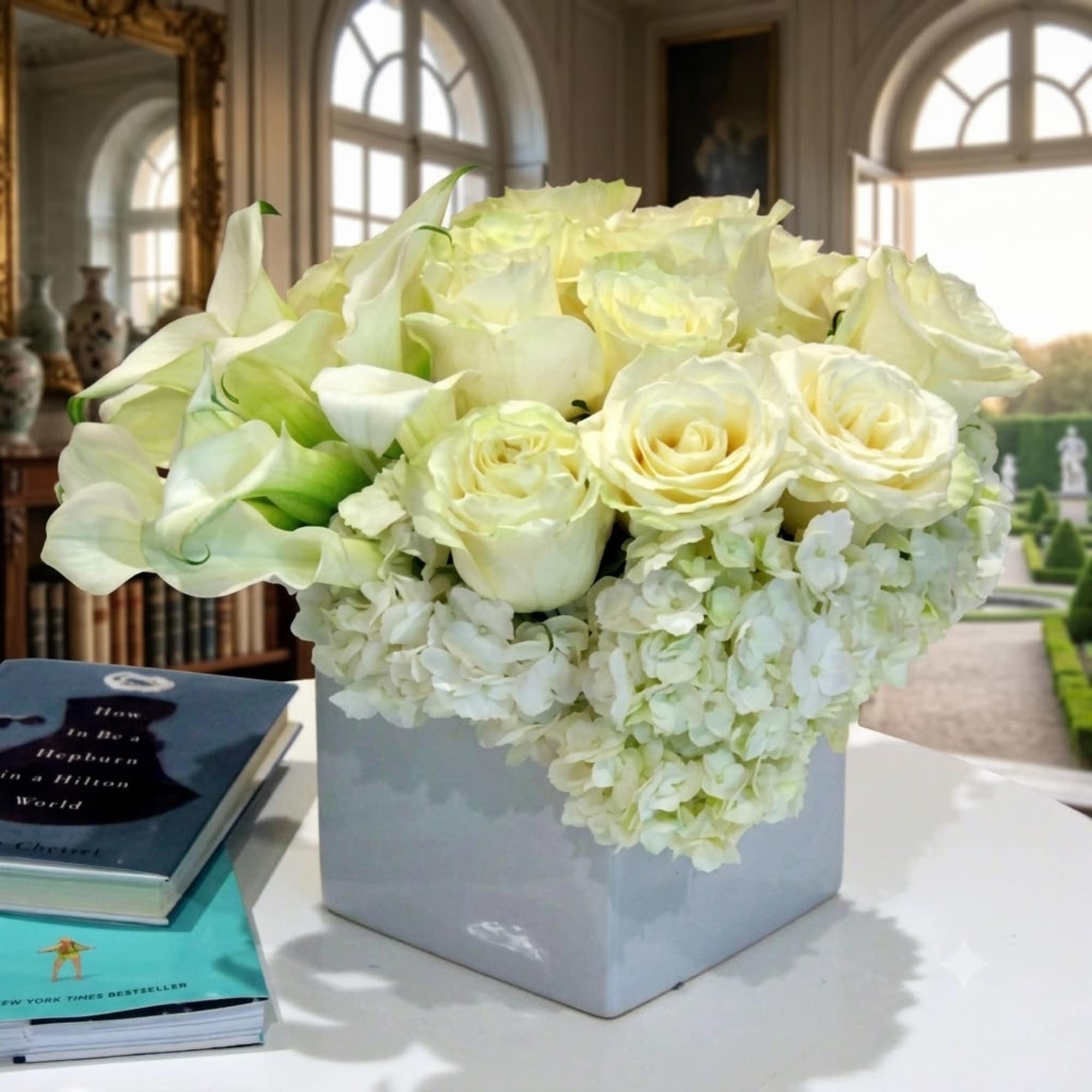 White roses and calla lilies arranged in a square vase