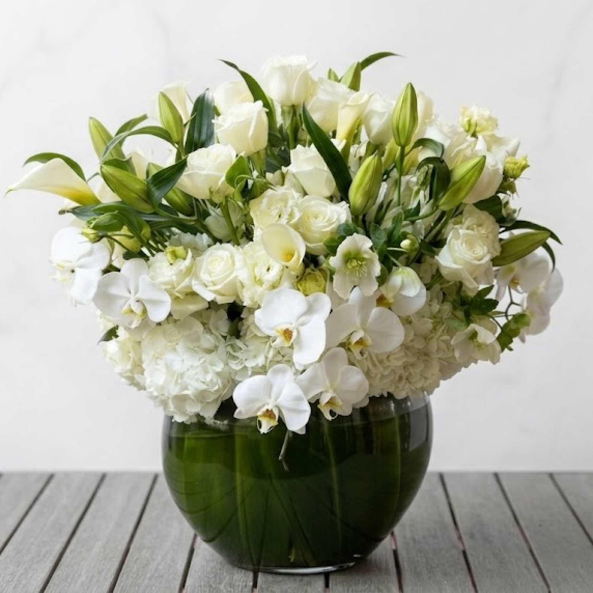 White floral arrangement in a dark green glass vase
