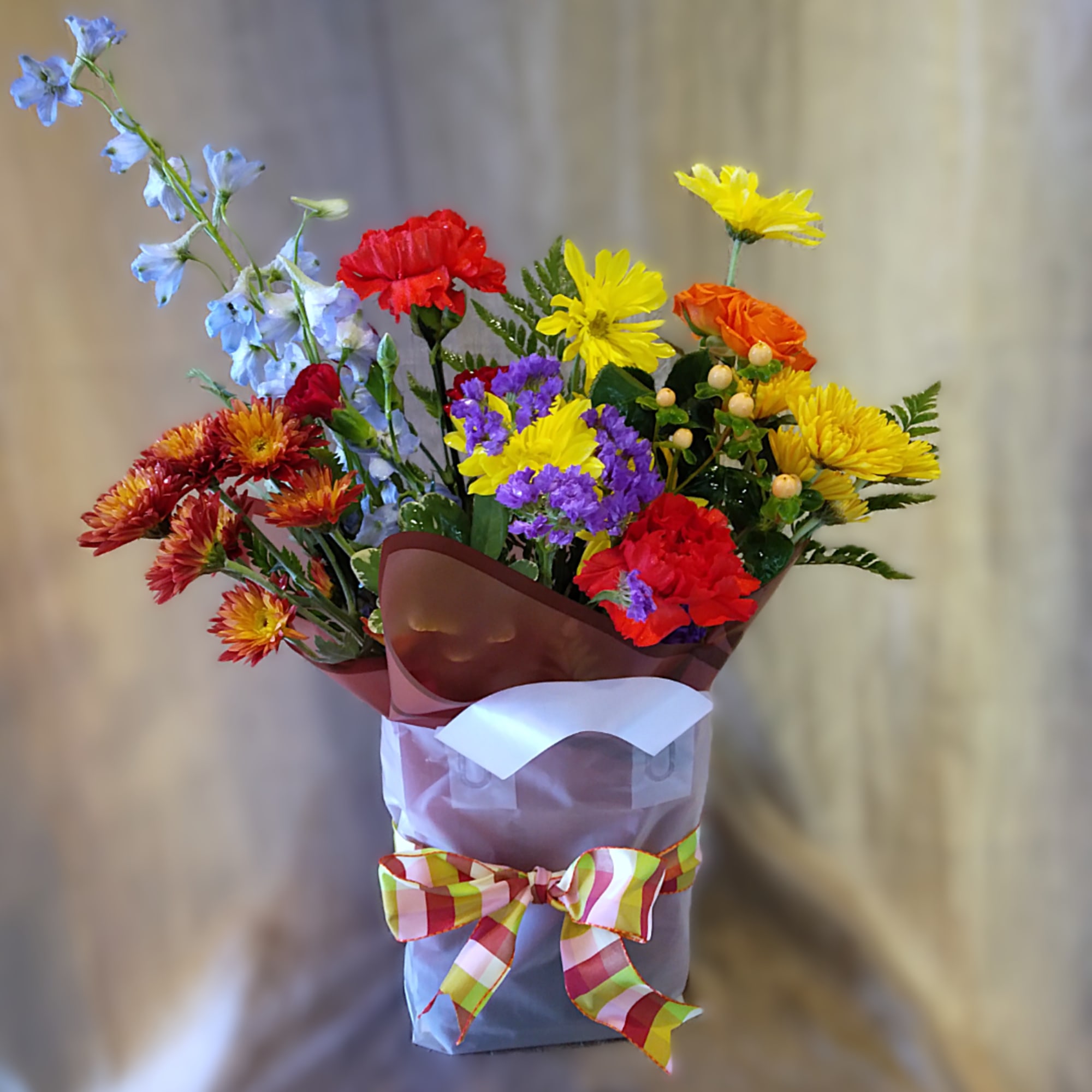 Colorful mixed bouquet with daisies, carnations, and purple filler in a wrapped box
