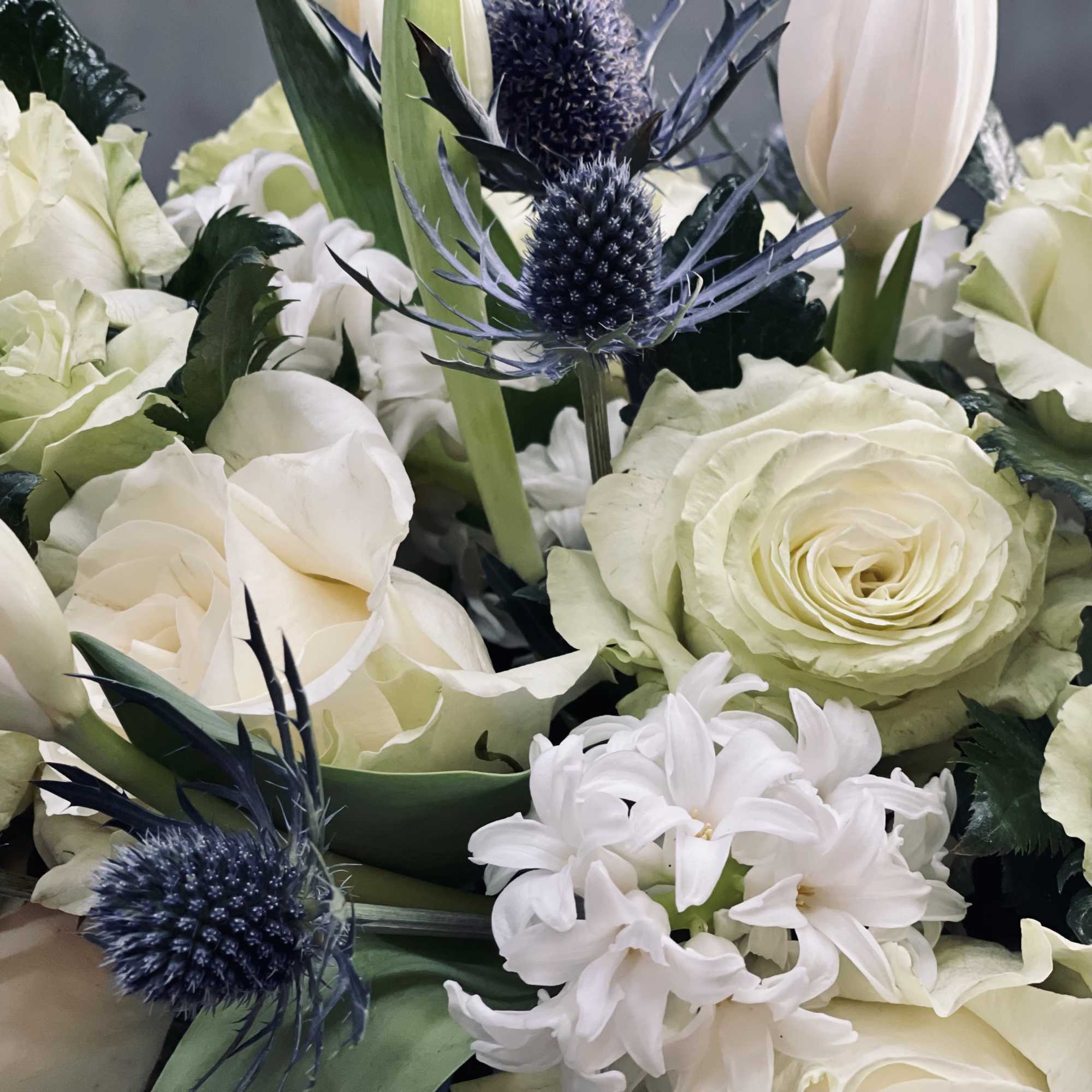 A cluster of white tulips, roses, hyacinths and thistle in a bejeweled, photo 2 of 2