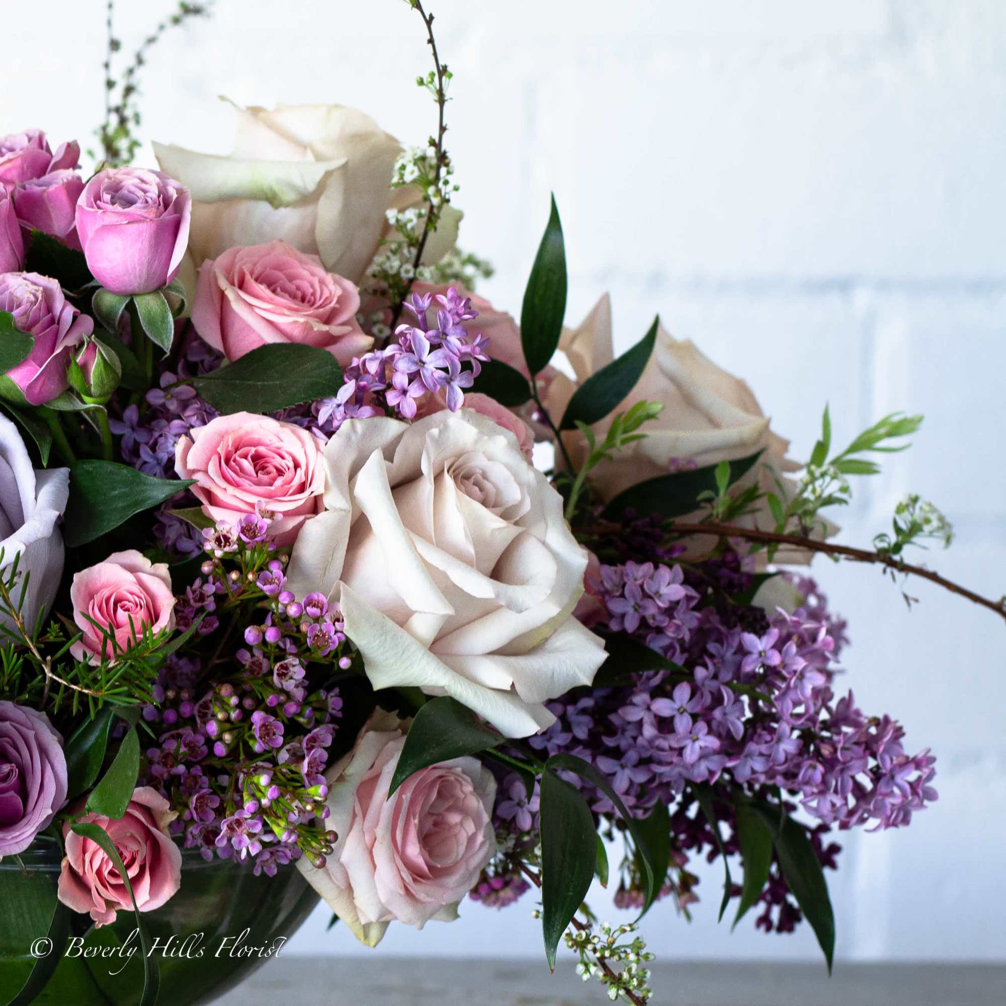 A beautiful floral arrangement featuring local lilacs and soft-colored roses set in, photo 3 of 3