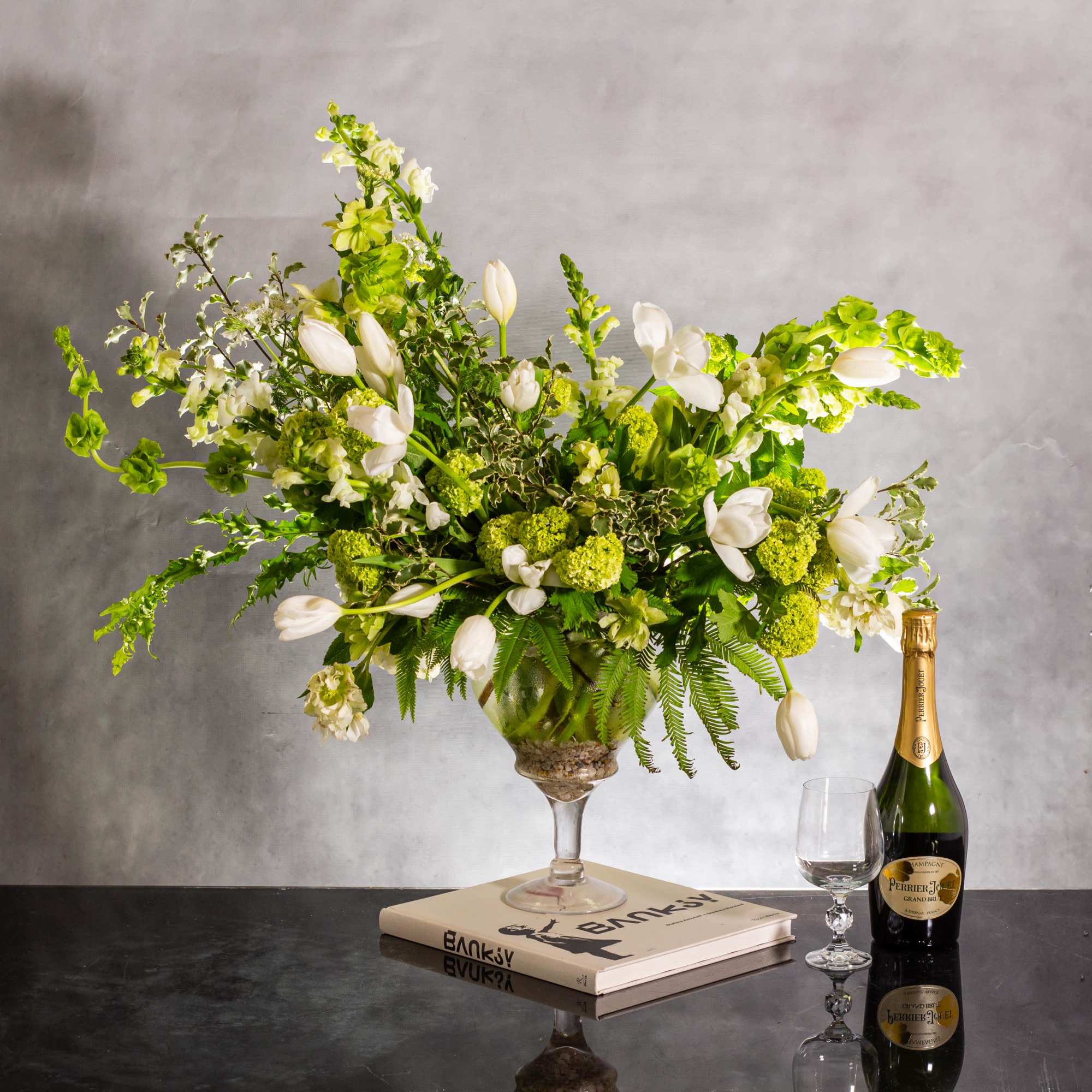 The beautiful arrangement features long white tulips, snapdragons, boulevard beautiful umbrella ferns