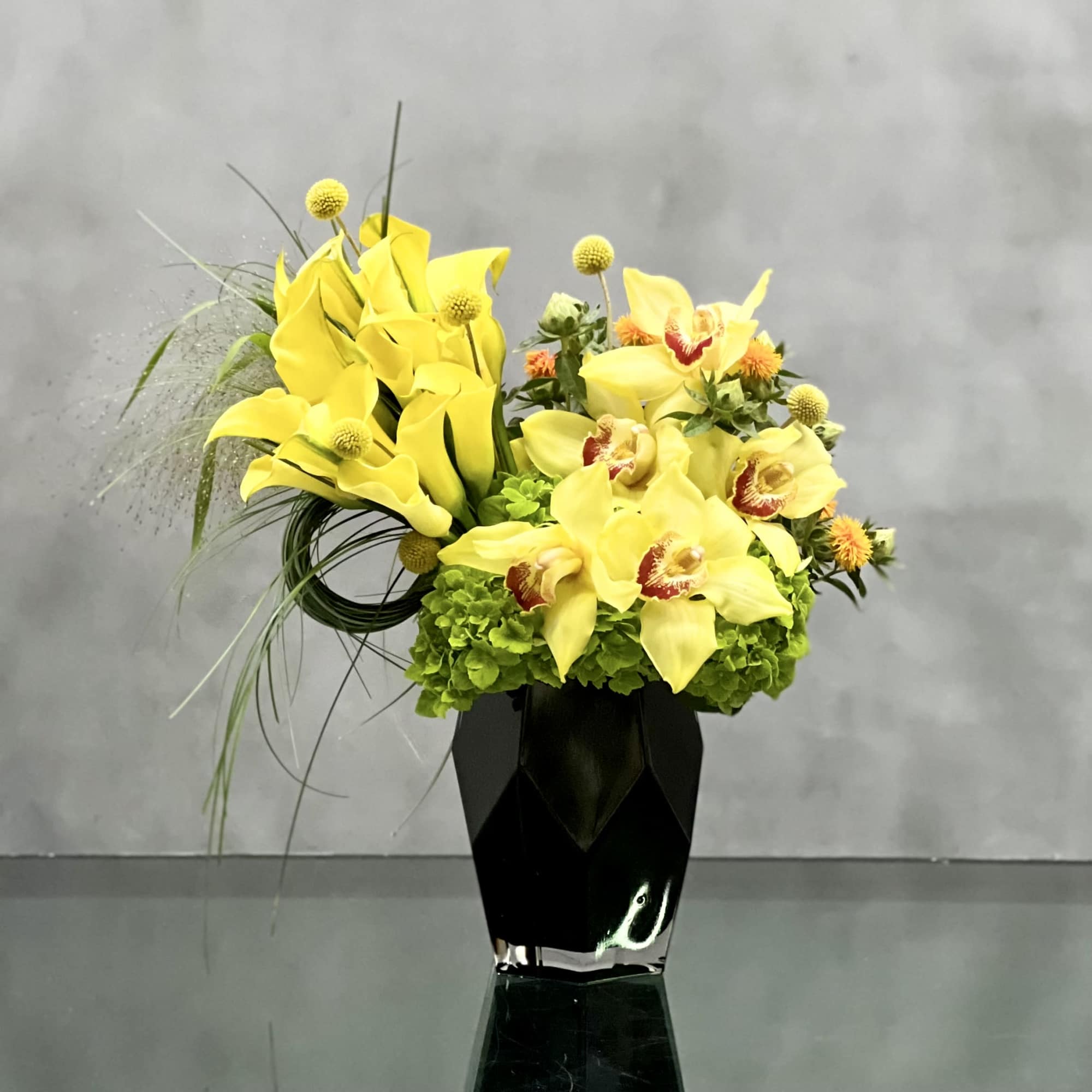 Golden Cymbidium Orchid pairs with yellow calla lilies in a black geometric