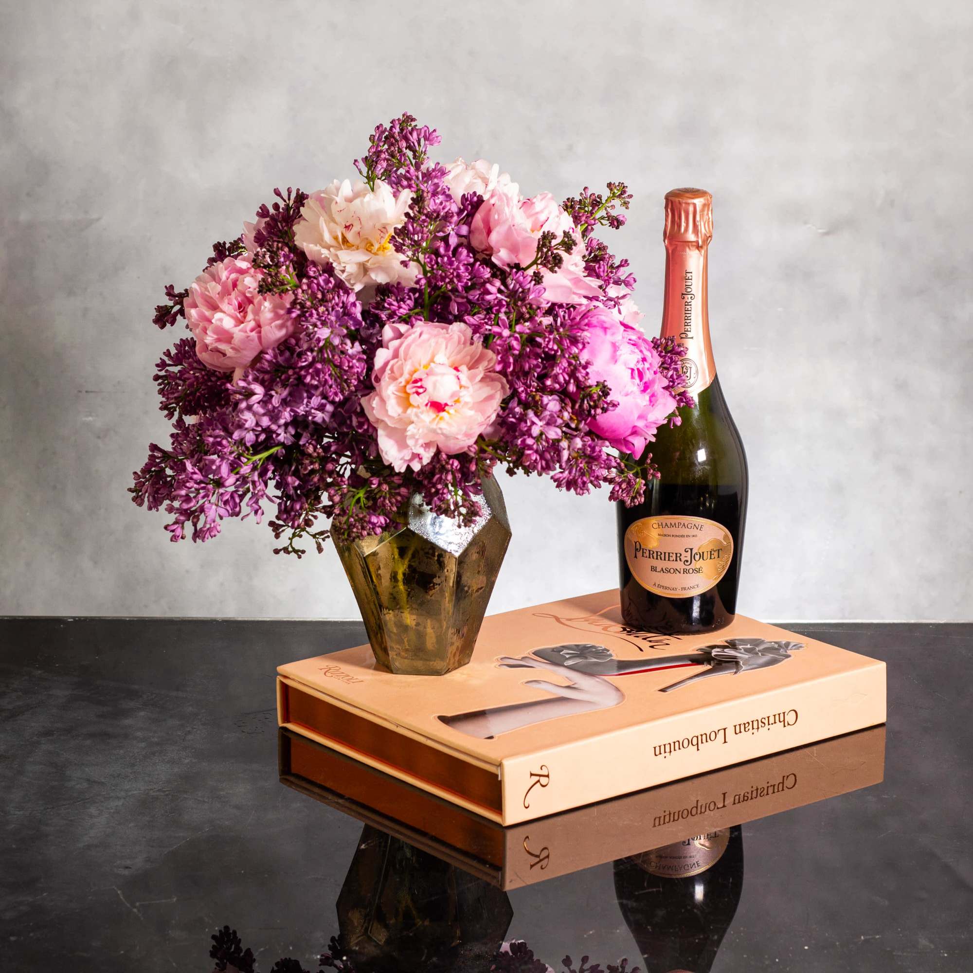 The beautiful arrangement features blush color peonies and purple lilacs gathered together