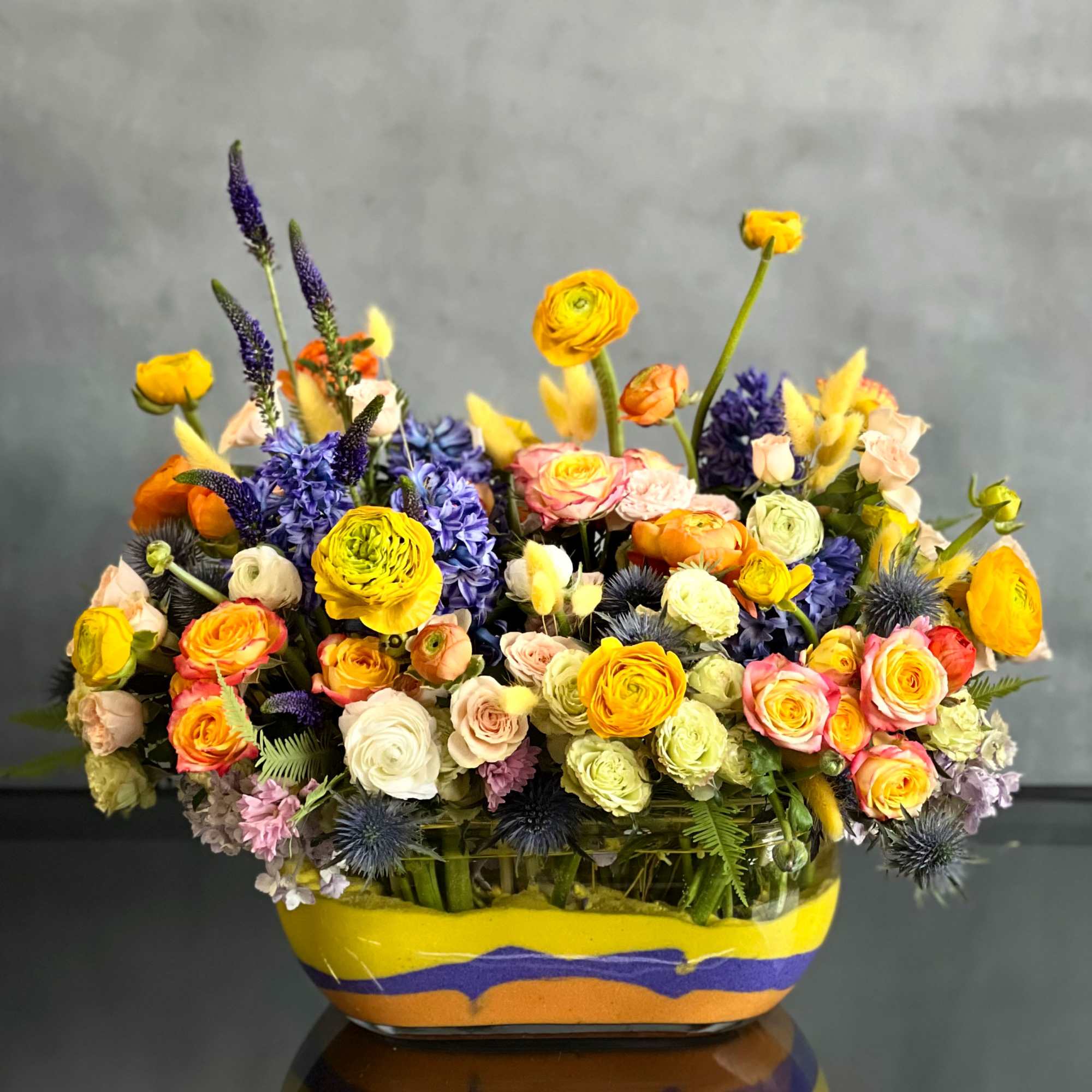 The design features elegant splashes of yellow ranunculus, orange, peach and white