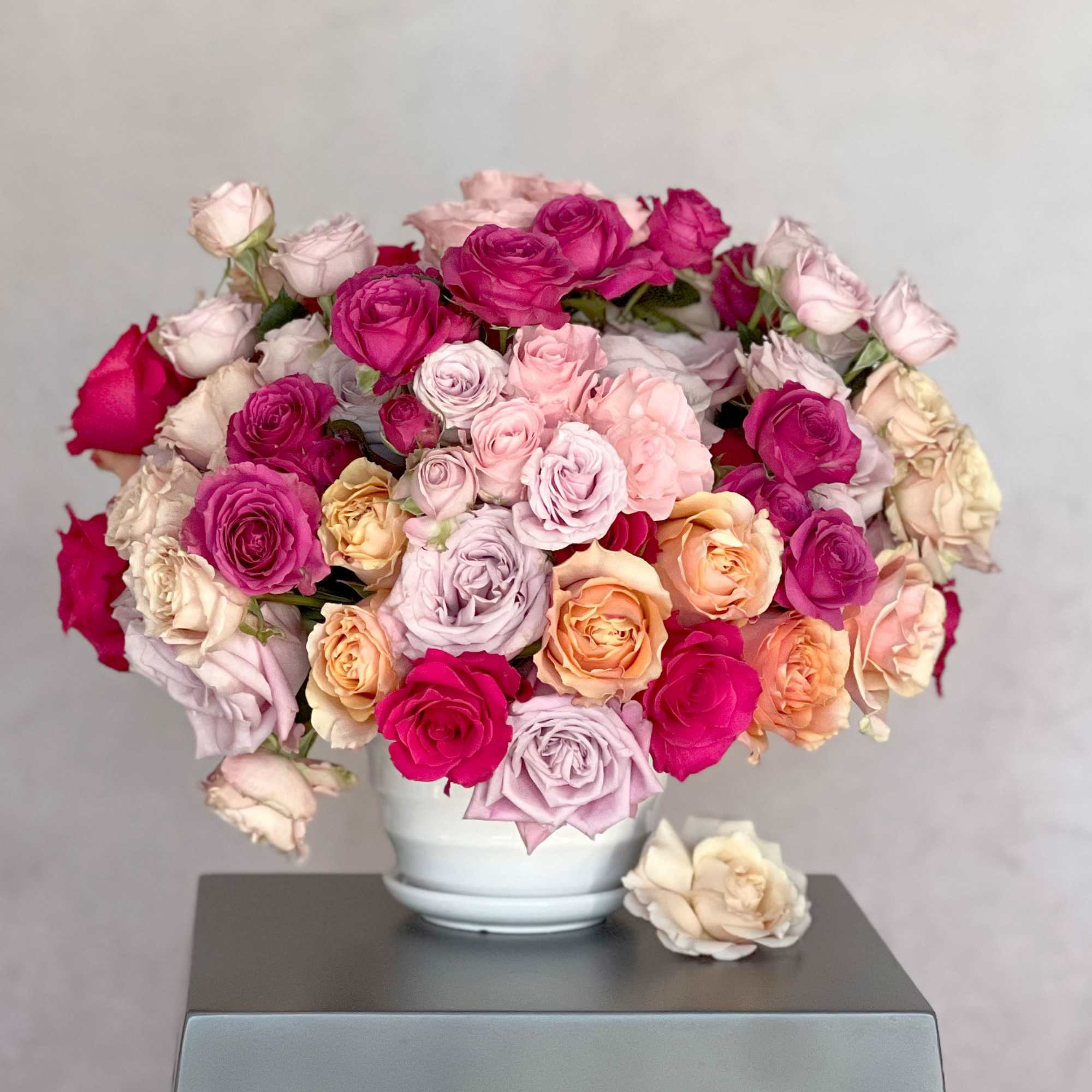 Bouquet of pink, peach, and cream roses in a white vase