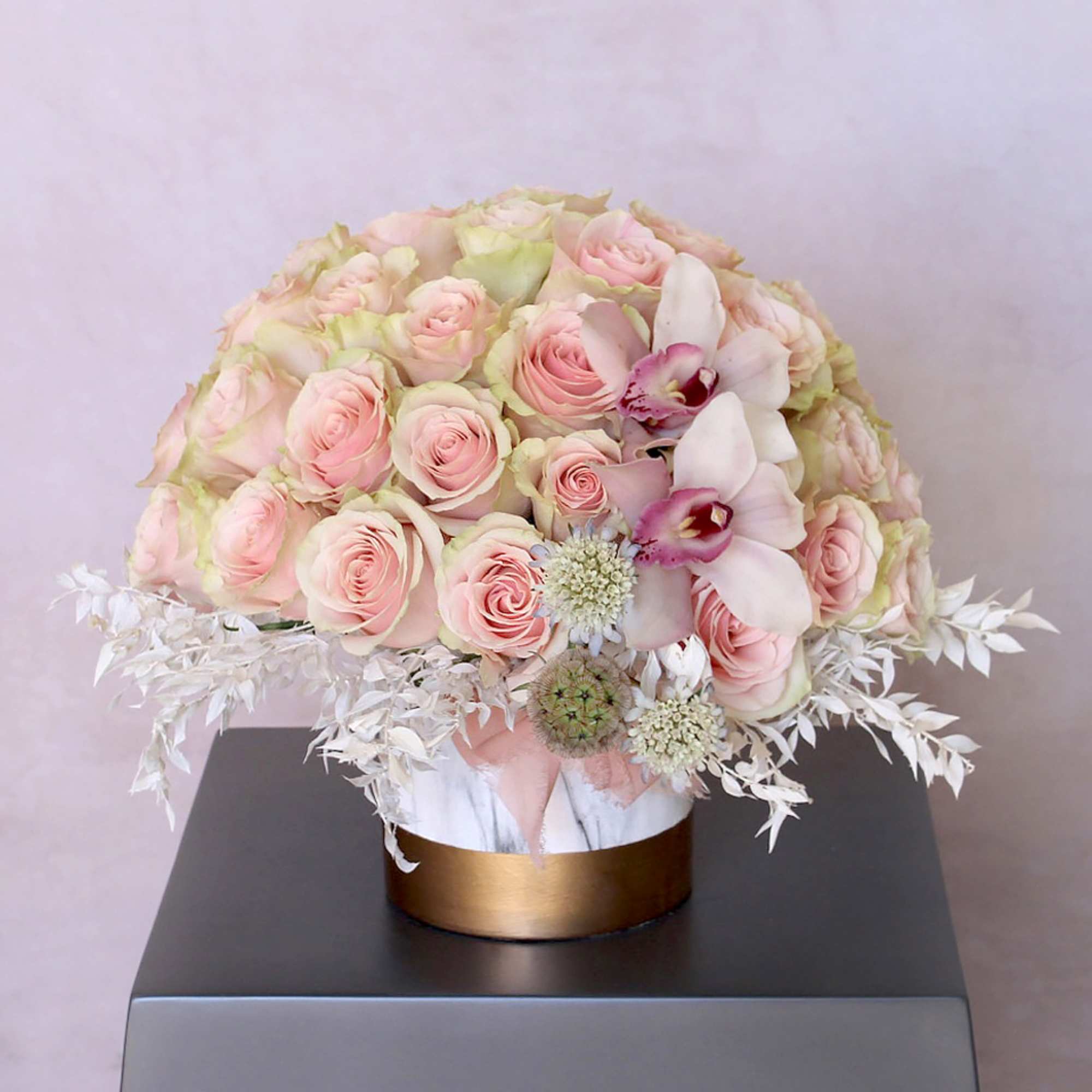 Round bouquet of pale pink roses and white orchids in a gold box