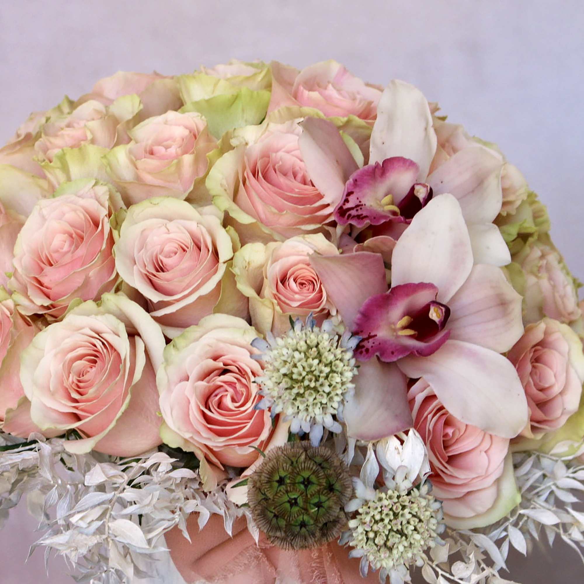 Bouquet of pale pink roses with white orchids and small accent blooms