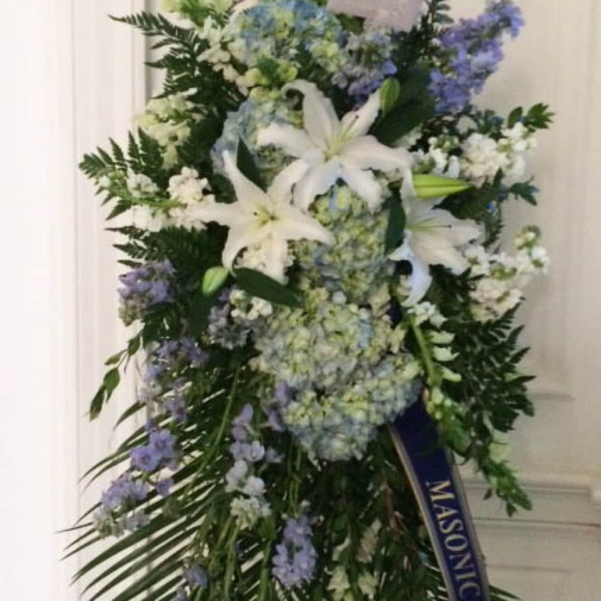 Standing floral spray with white lilies, blue hydrangeas, and purple flowers