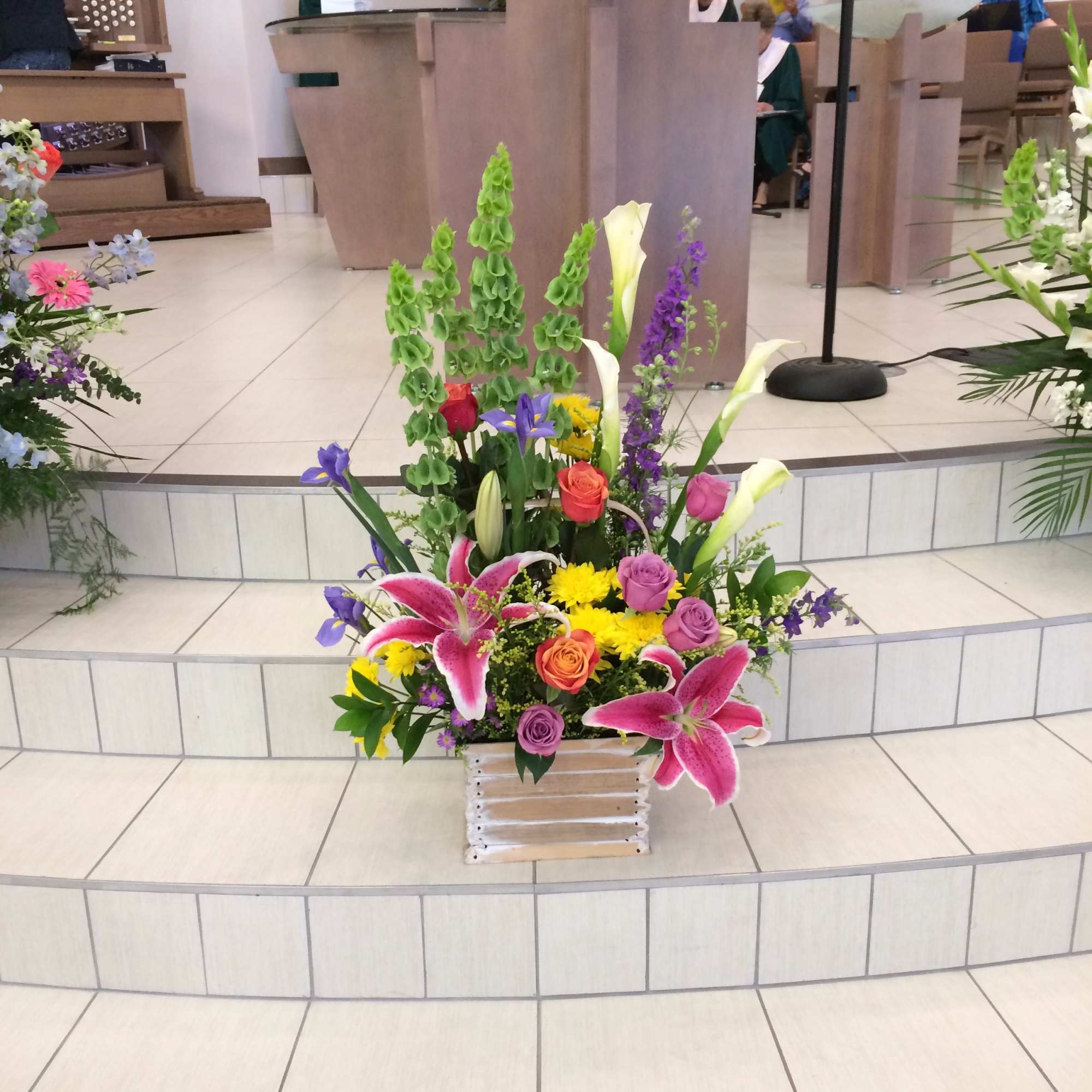 Colorful floral arrangement with lilies, roses, and irises in a basket