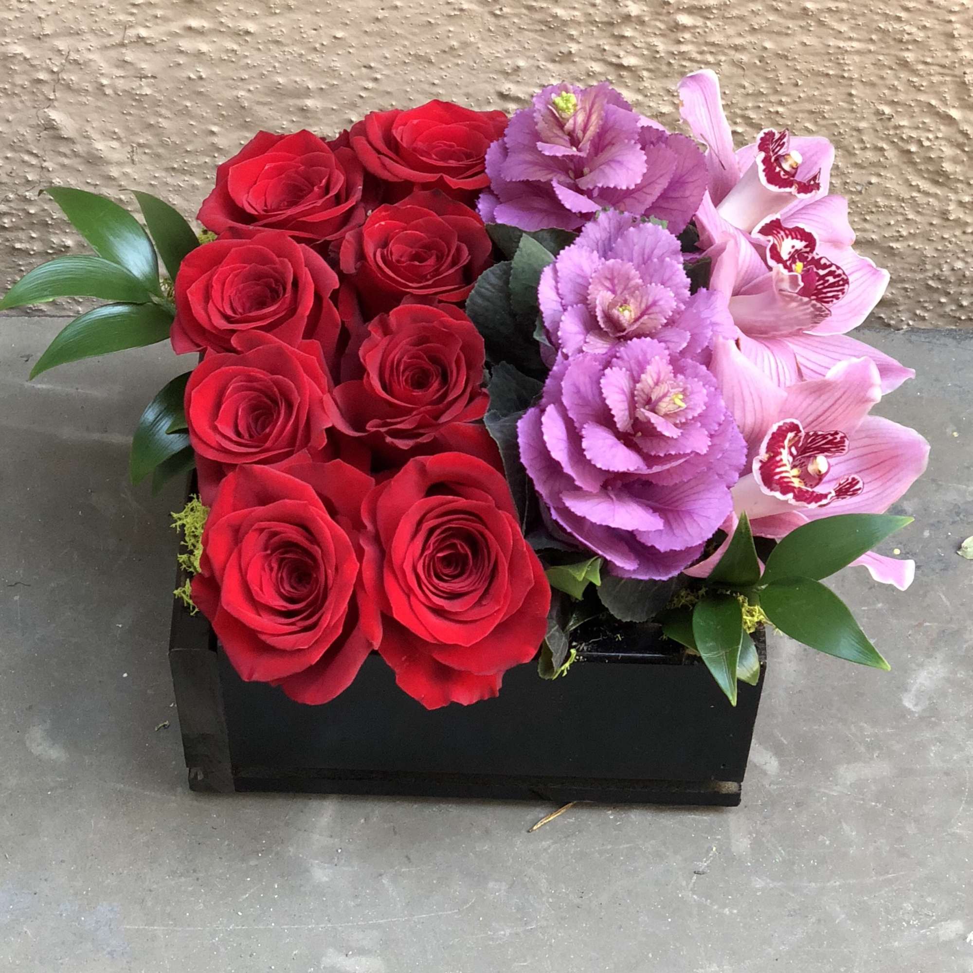 Red roses and pink orchids in a black rectangular box