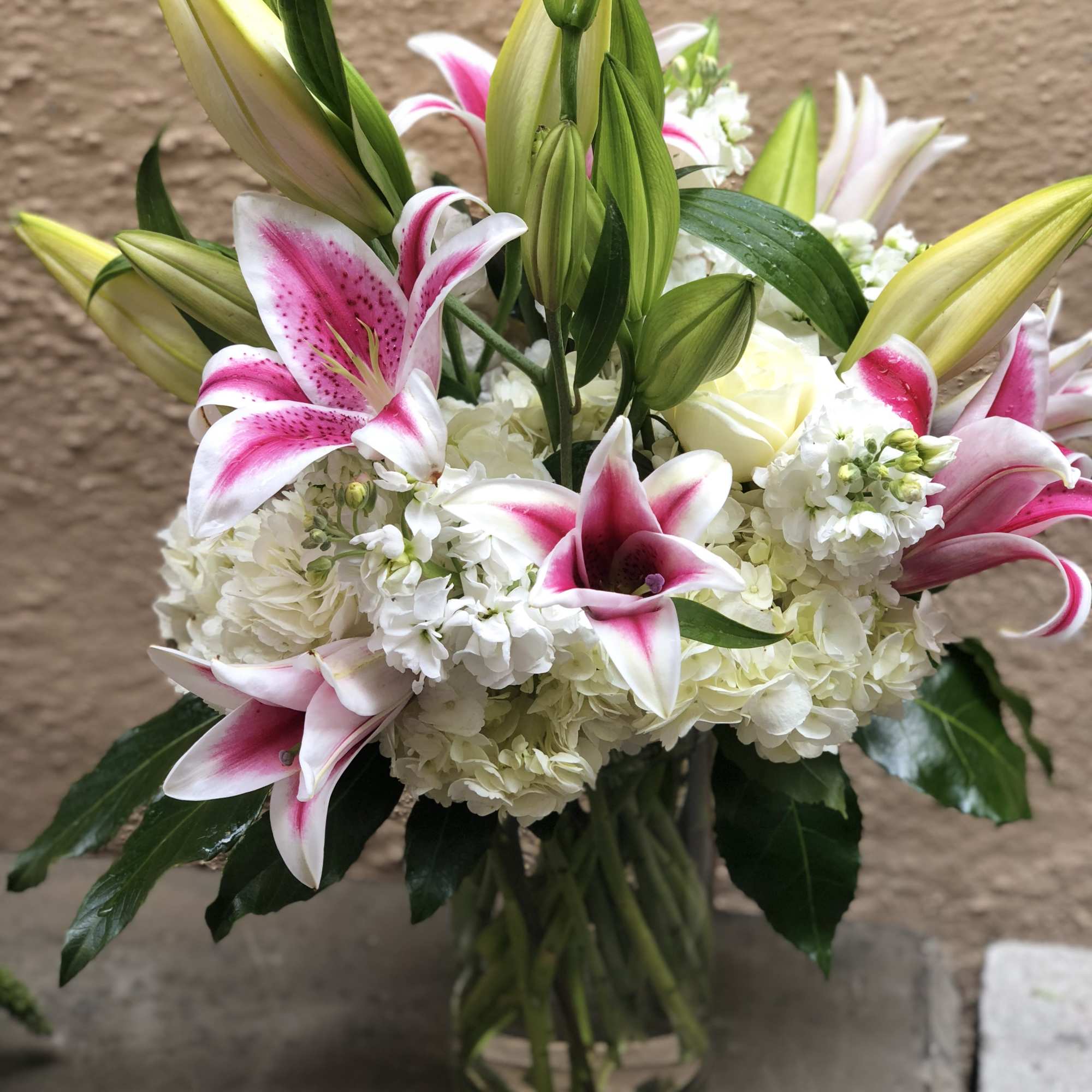 Bouquet of pink-and-white lilies and white hydrangeas in a glass vase