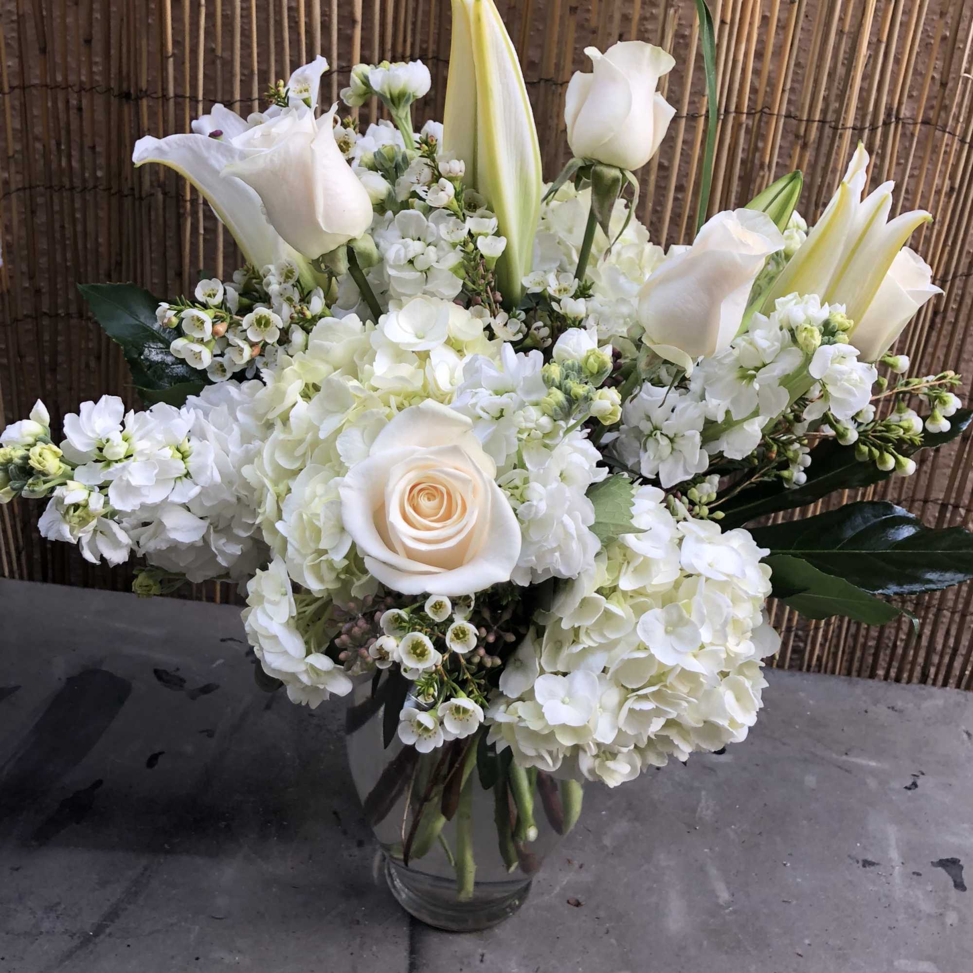 White roses, lilies, and hydrangeas in a glass vase