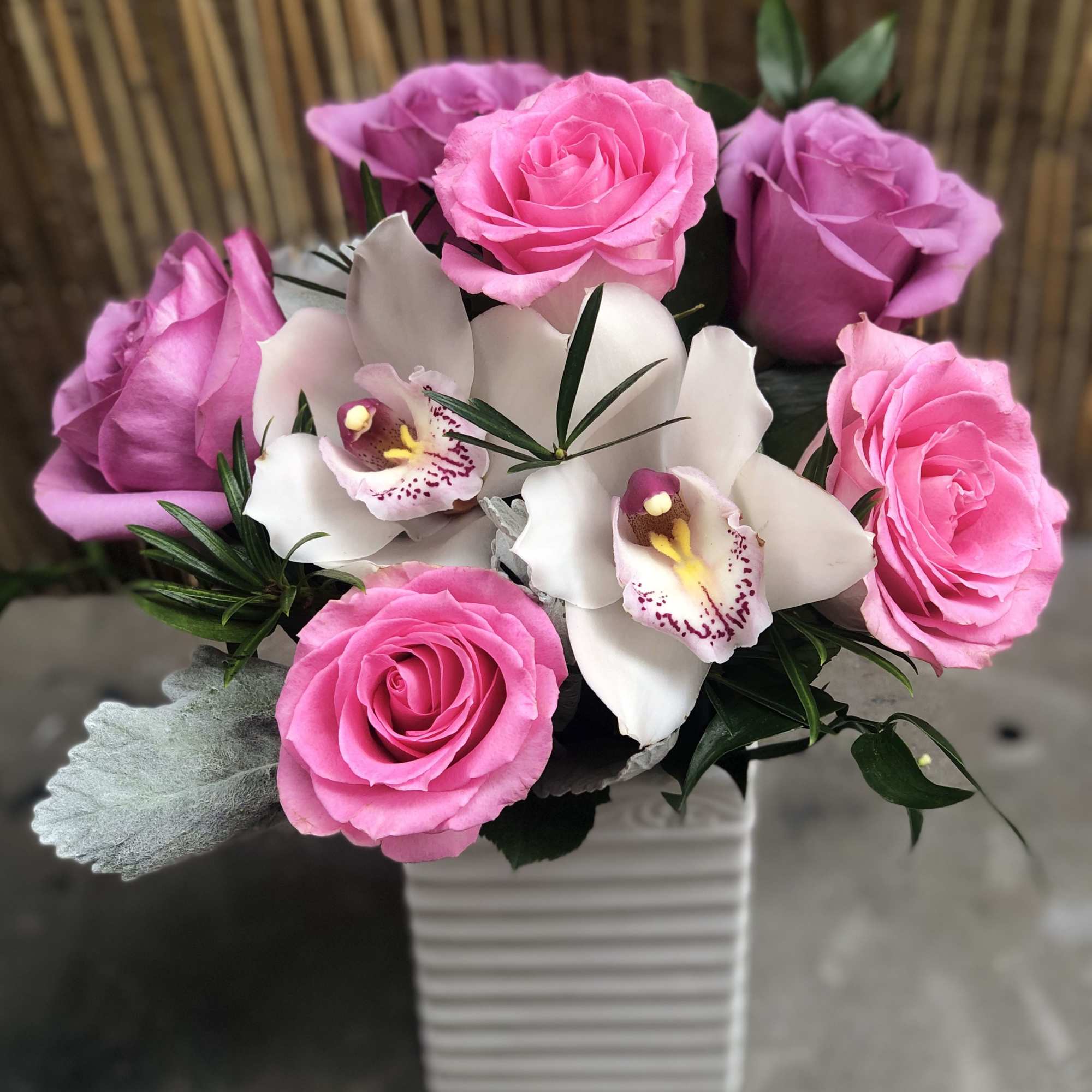 Pink roses and white orchids in a striped ceramic vase