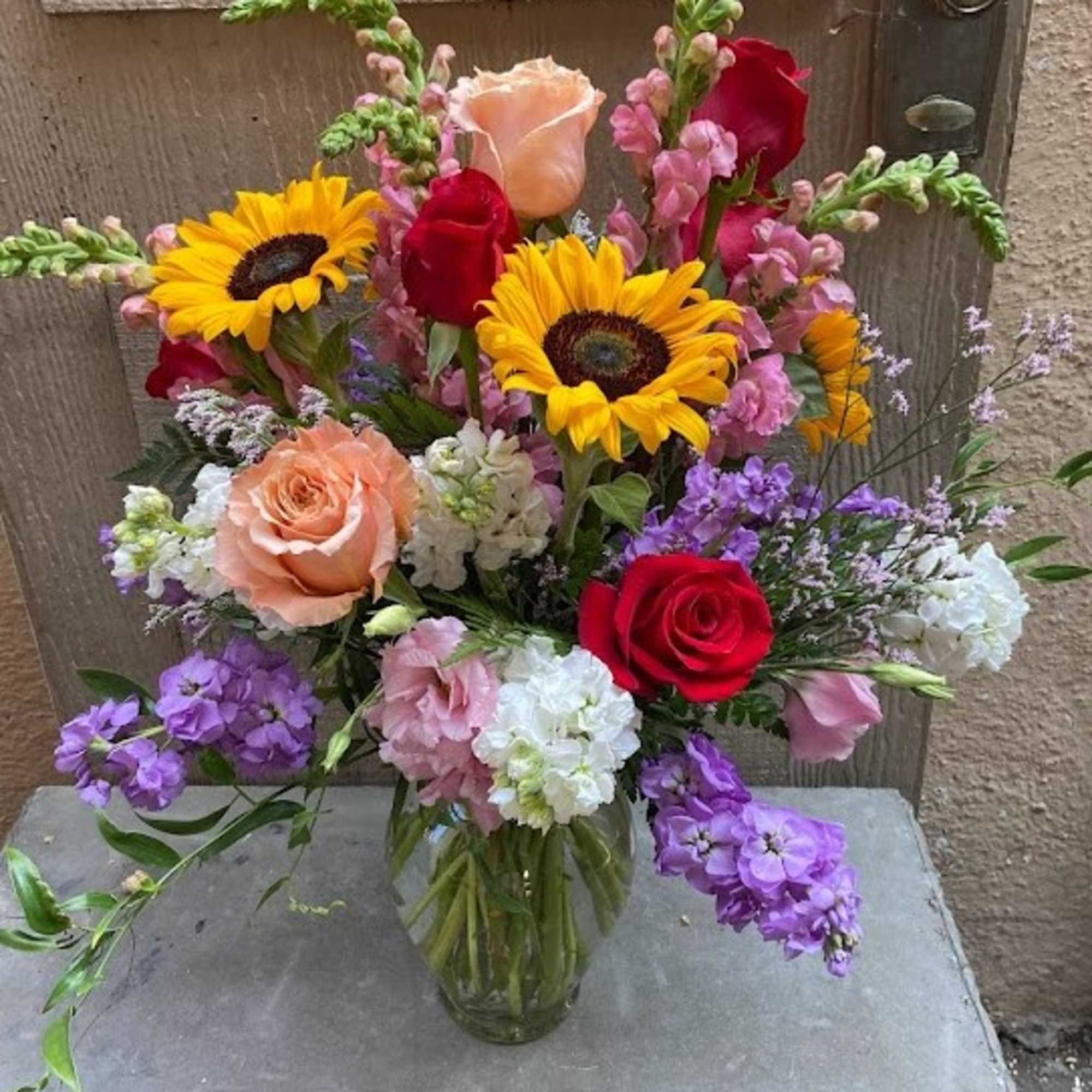 Mixed bouquet in a glass vase with sunflowers and roses