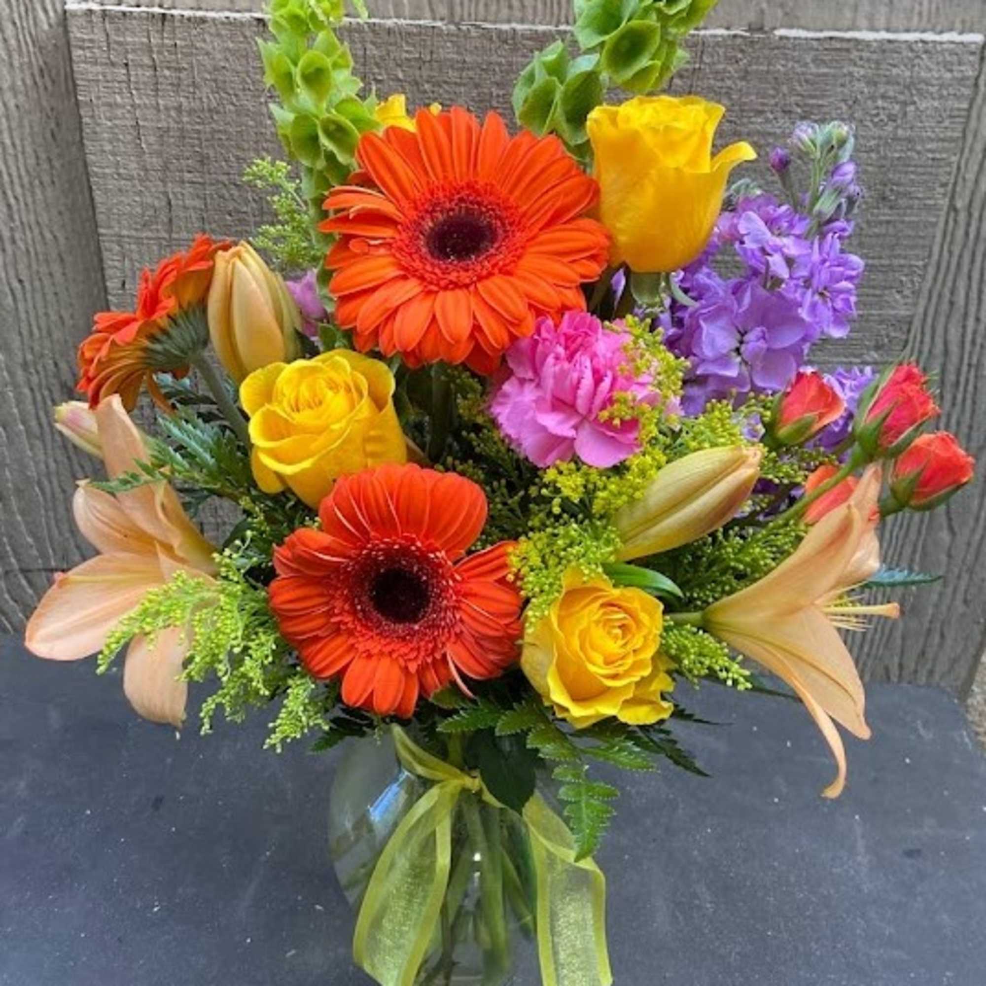 Bright mixed bouquet in a glass vase with orange gerberas and yellow roses